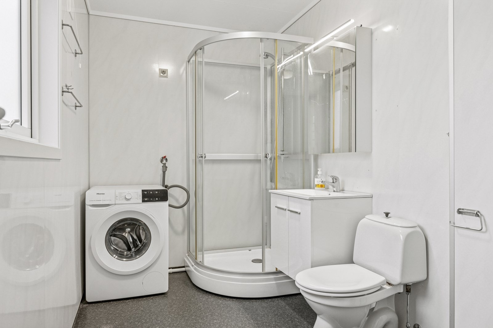 Baderom med baderomsseksjon med vask, speilskap, dusj og wc.
Opplegg for vaskemaskin. Galleribilde