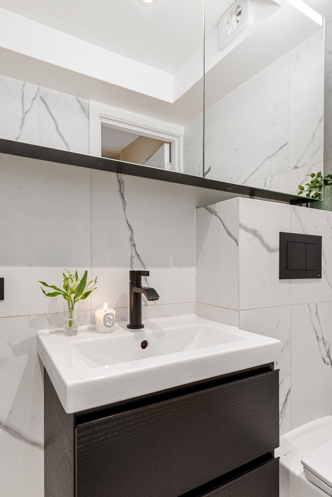 Baderommet er innredet med vegghengt klosett, servant nedfelt i innredning, speilskap med lys og dusjhjørne med foldedører. Galleribilde