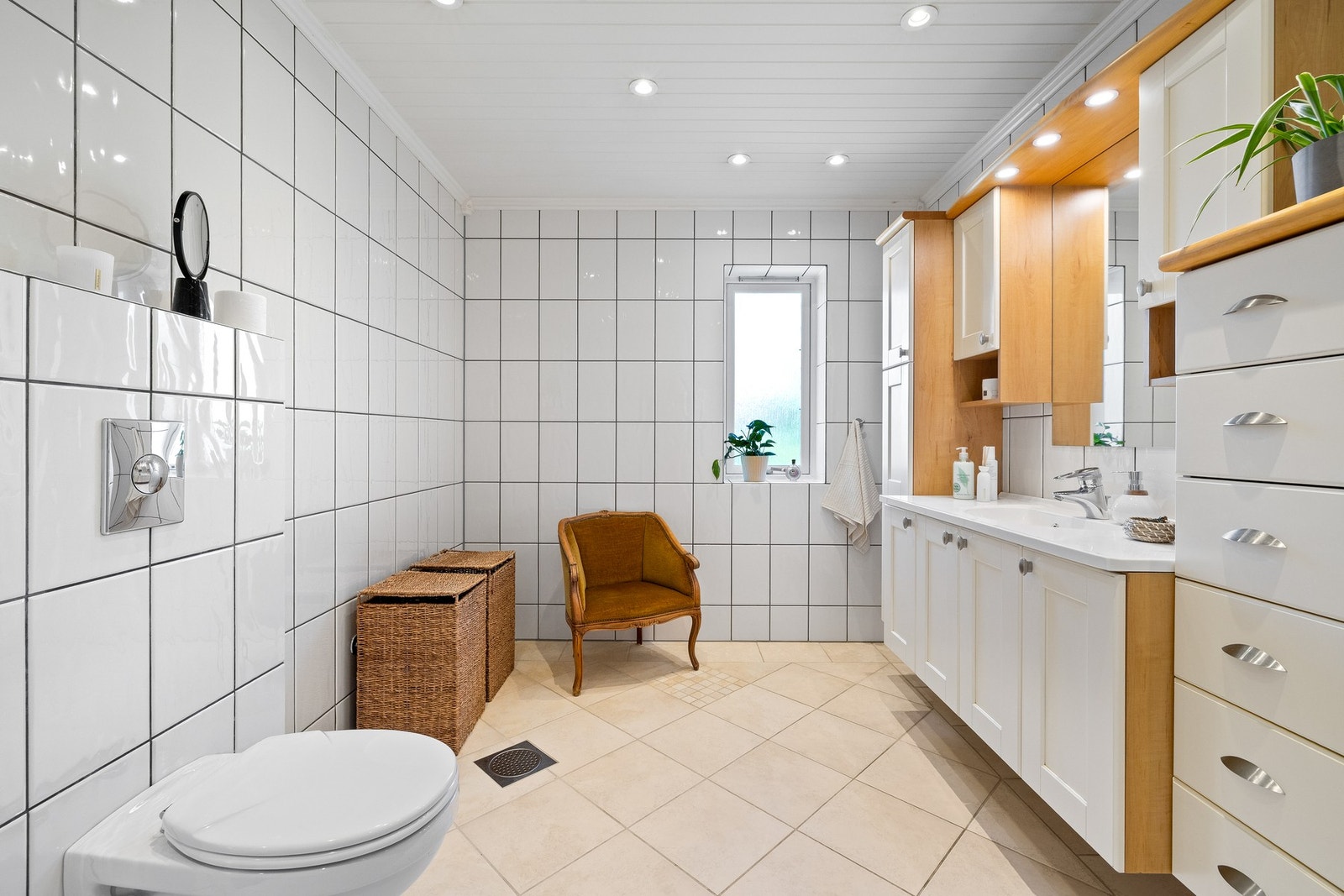 Baderomsinnredningen har hvite fronter og består av en heldekkende servant på en skapseksjon, to sideskap, to veggskap og et stort speil med belysning. Galleribilde
