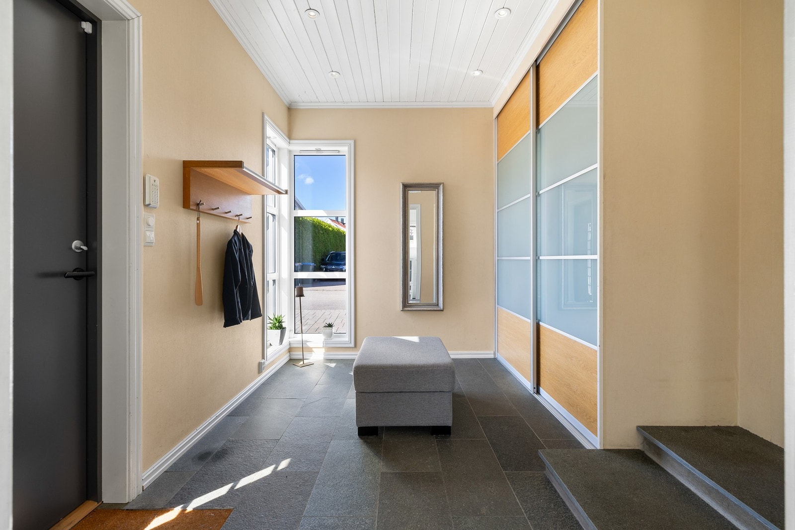 Vel inne blir vi ønsket velkommen i en romslig og fin entré med lysmalte vegger, downlights i himlingen og grå fliser på gulv med gulvvarme. Galleribilde