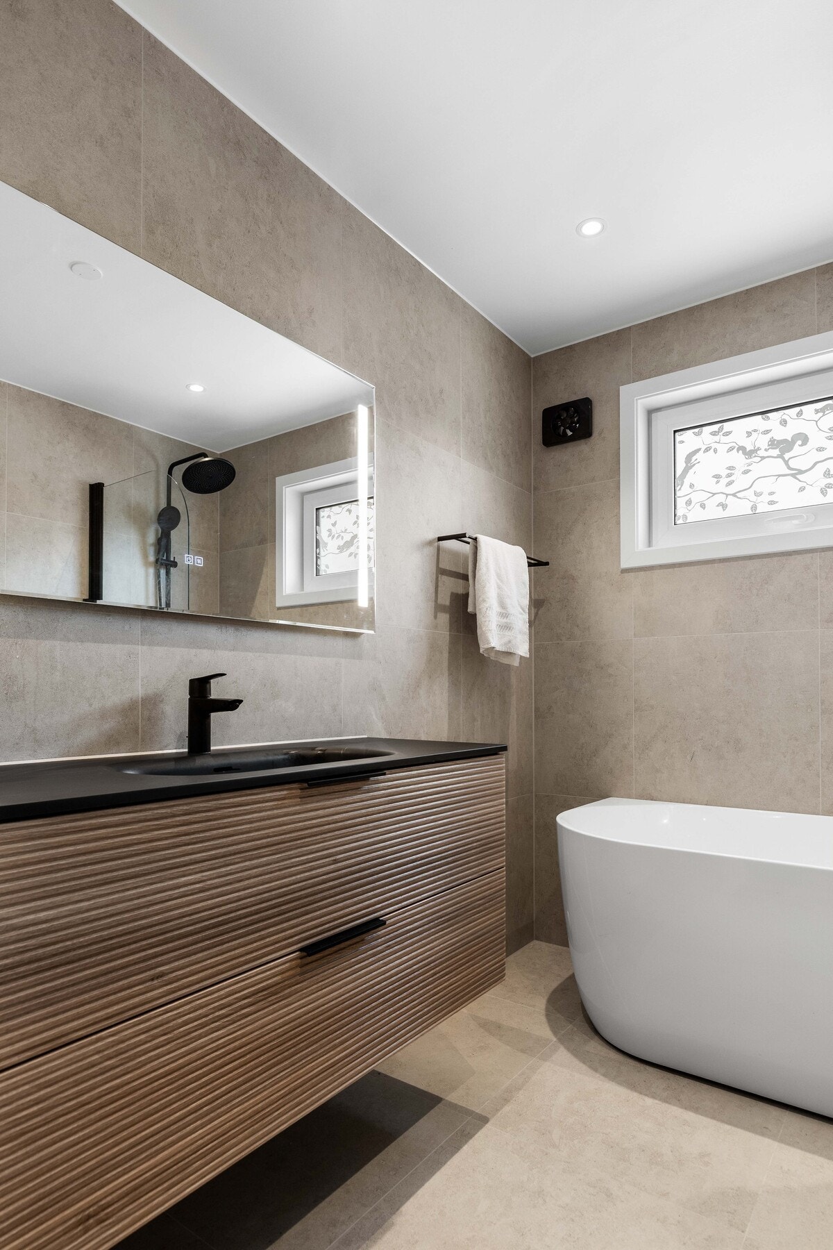 Store beige fliser på både vegger og gulv gir et tidløst uttrykk, og varmekabler sørger for en behagelig temperatur. Galleribilde