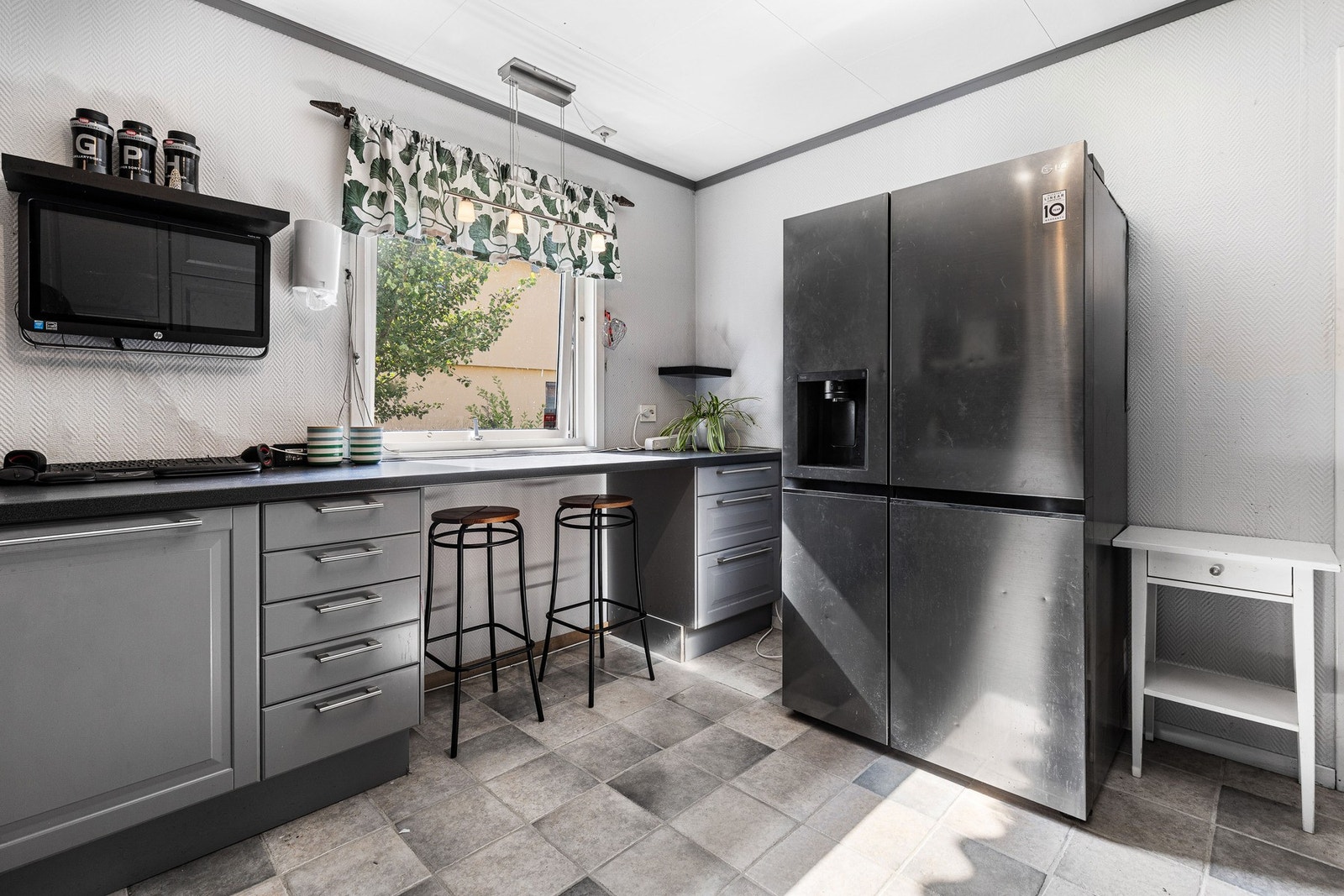 Løsningen fra 2014, levert av Ikea, byr på profilerte fronter, laminert benkeplate med nedfelt vaskekum og god oppbevaringsplass i både skap, hyller og vitrineskap. Galleribilde