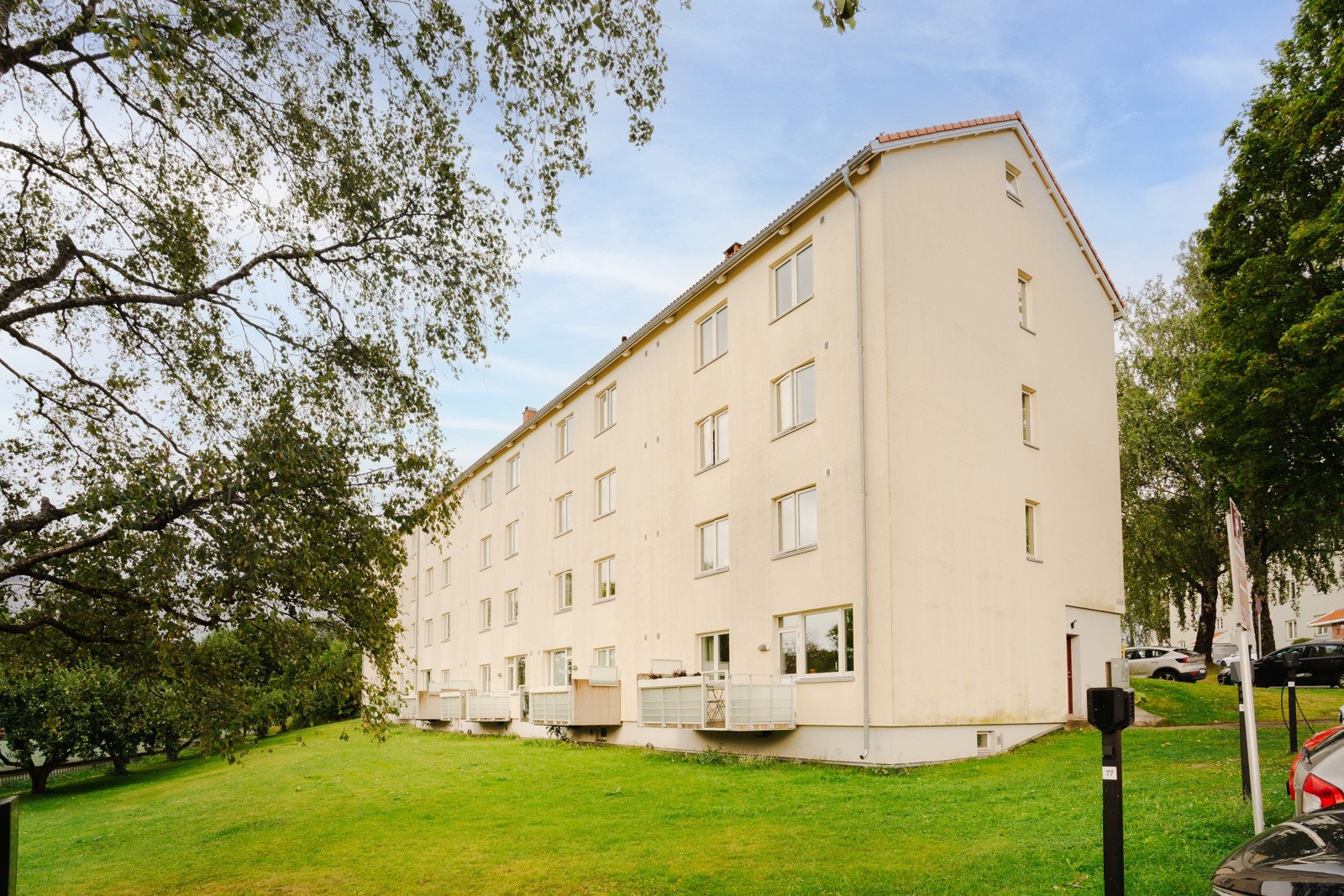 Boligen er plassert godt opp fra bakkeplan i skrånende terrreng mot frodige fellesareal. Galleribilde