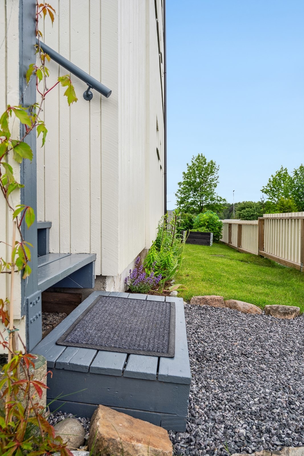 Innbydende inngangsparti med plenområde som disponeres av eier av leiligheten. I dag beplantet med bærbusker, plen og planter. Galleribilde