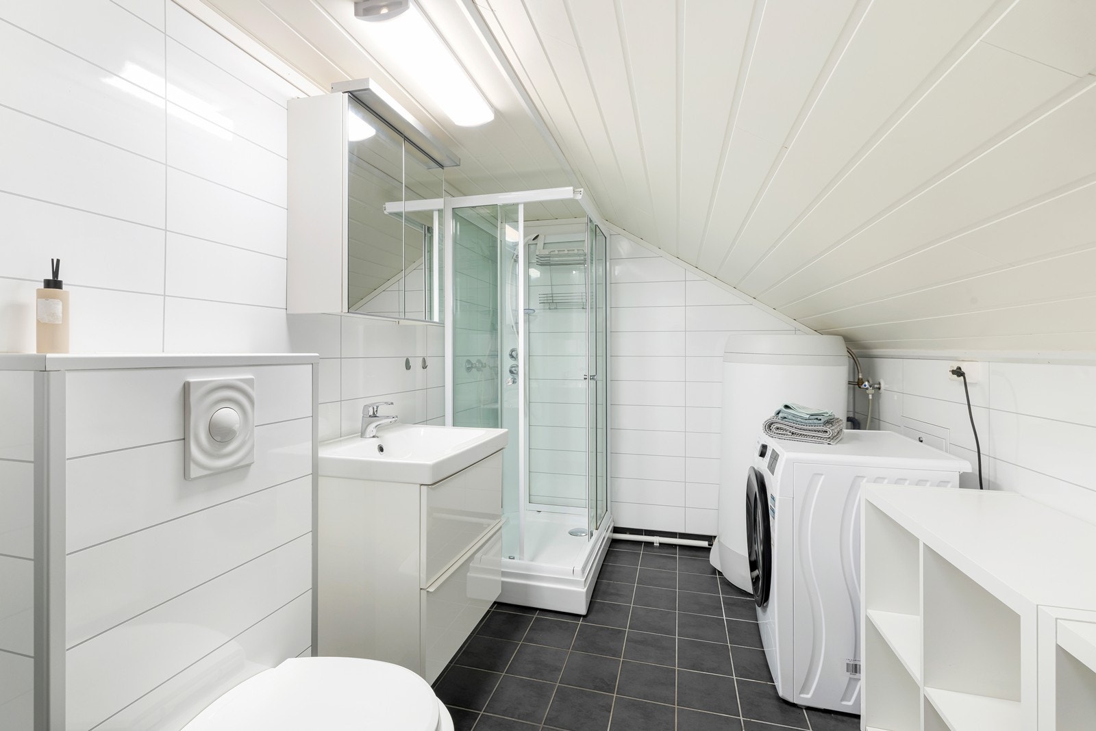 Flott flislagt bad med vamekabler i gulv og våtromsplater på vegger. Badet har dusjkabinett, servant med underskuffer og vegghengt toalett. Opplegg til vaskemaskin. Galleribilde