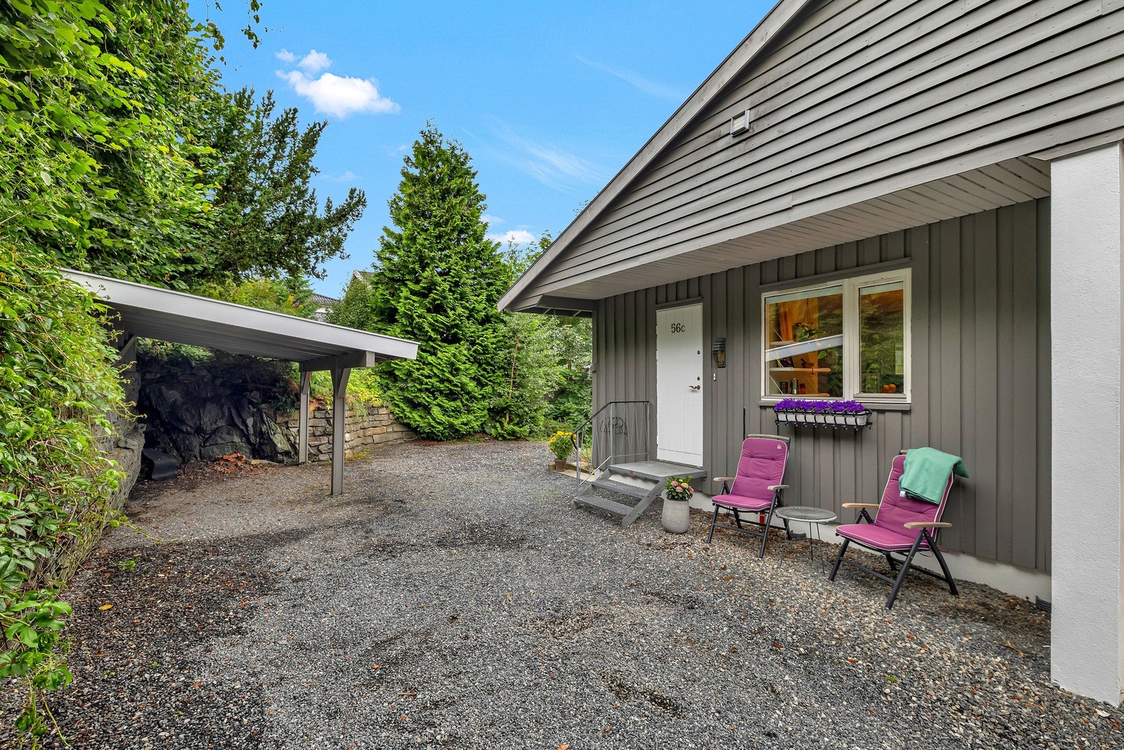 Gruslagt gårdsplass med parkering i carport. Galleribilde