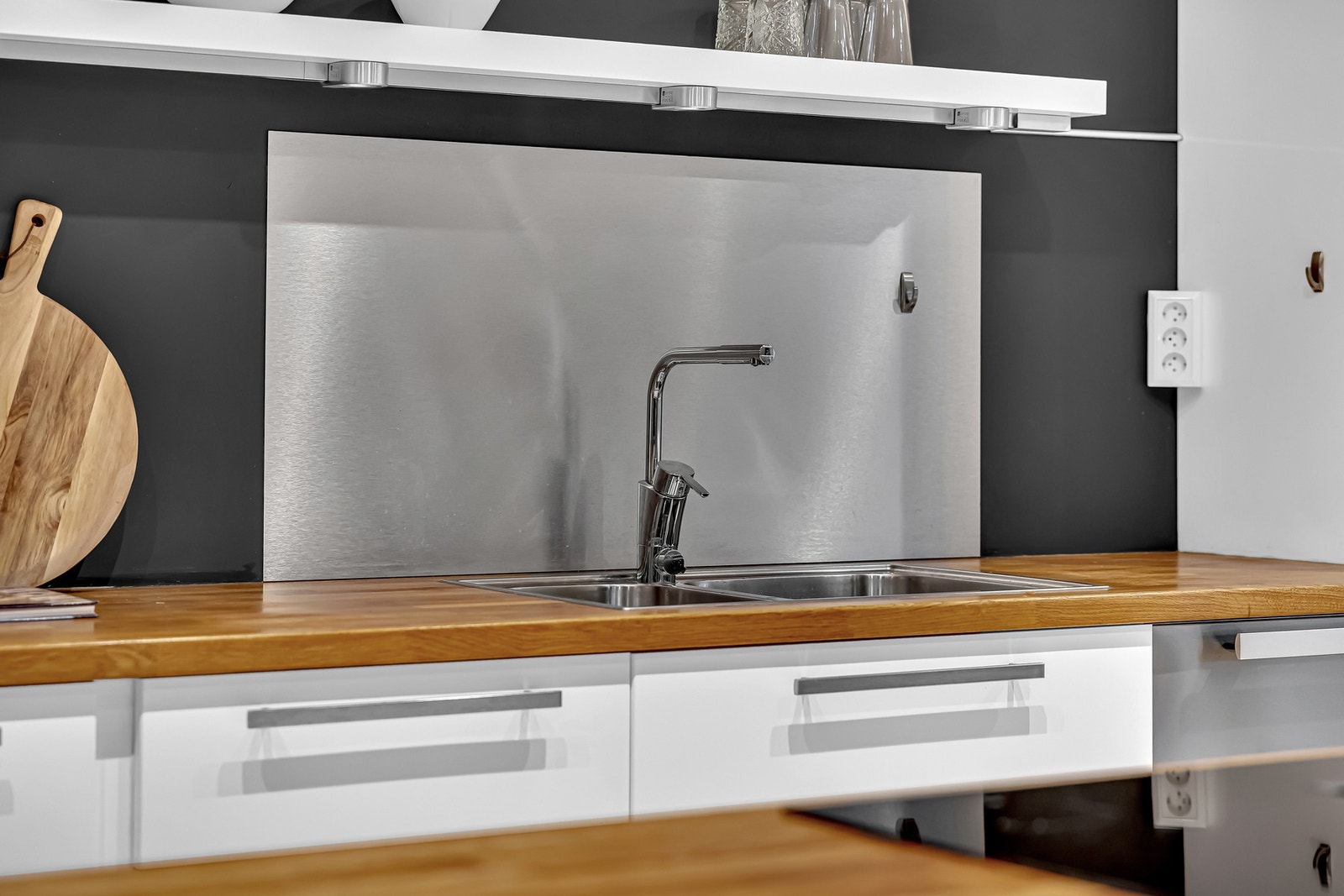 Den nedsenkede oppvaskkummen i metall med ett-greps armatur er plassert foran en praktisk sprutplate. Galleribilde