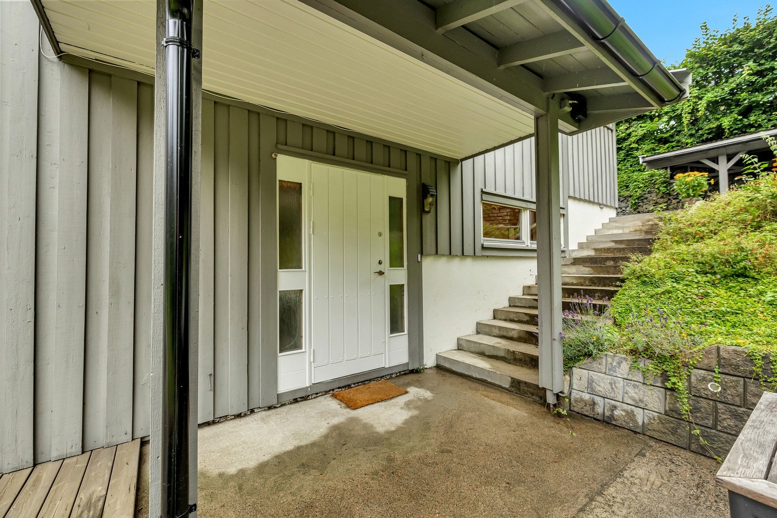 Det overbygde inngangspartiet gir en praktisk og innbydende inngang til boligen, hvor man er beskyttet mot vær og vind. Galleribilde