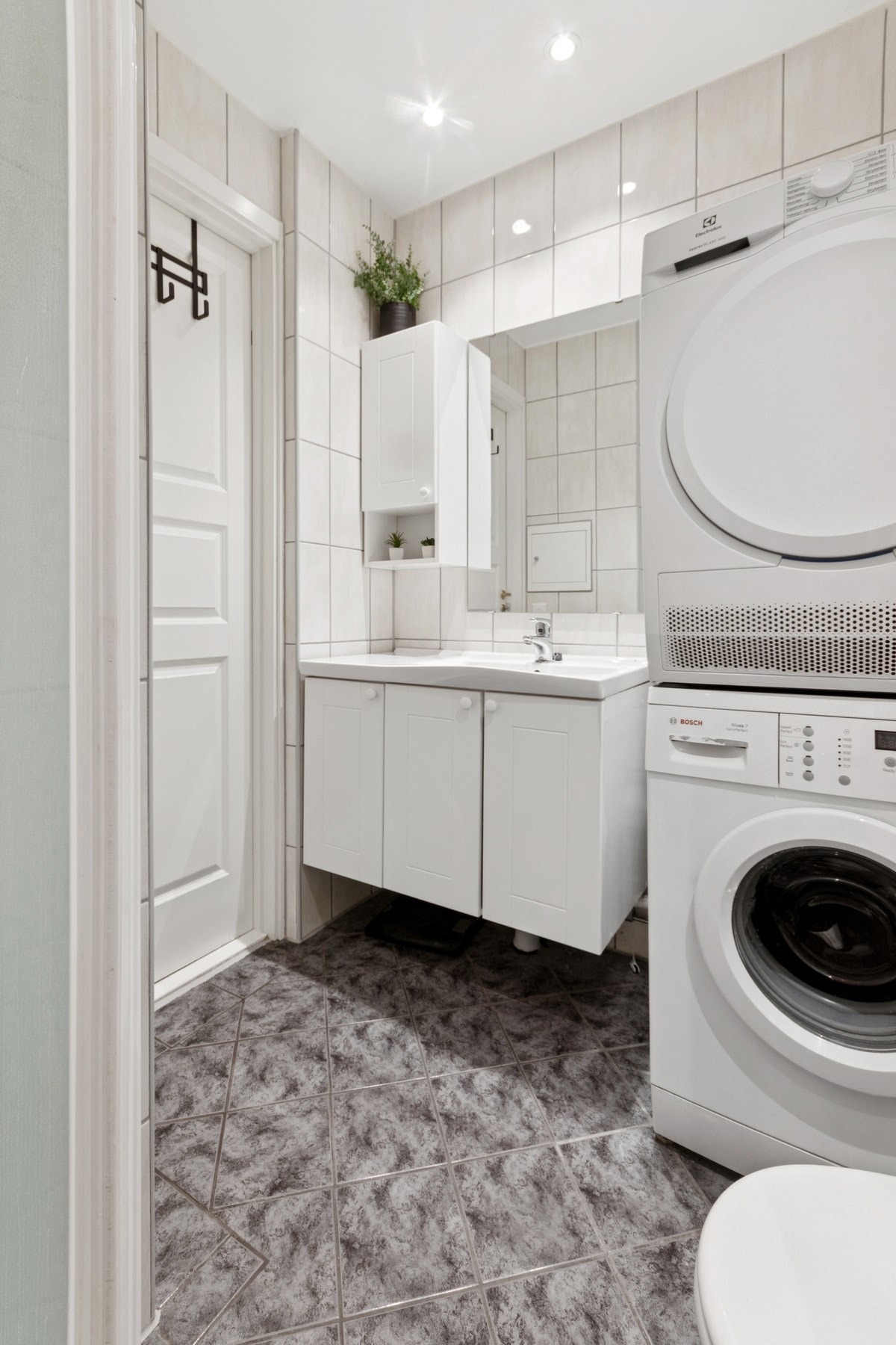 Rommet er innredet med nedfelt servant, toalett, dusjvegger/hjørne og opplegg for vaskemaskin Galleribilde