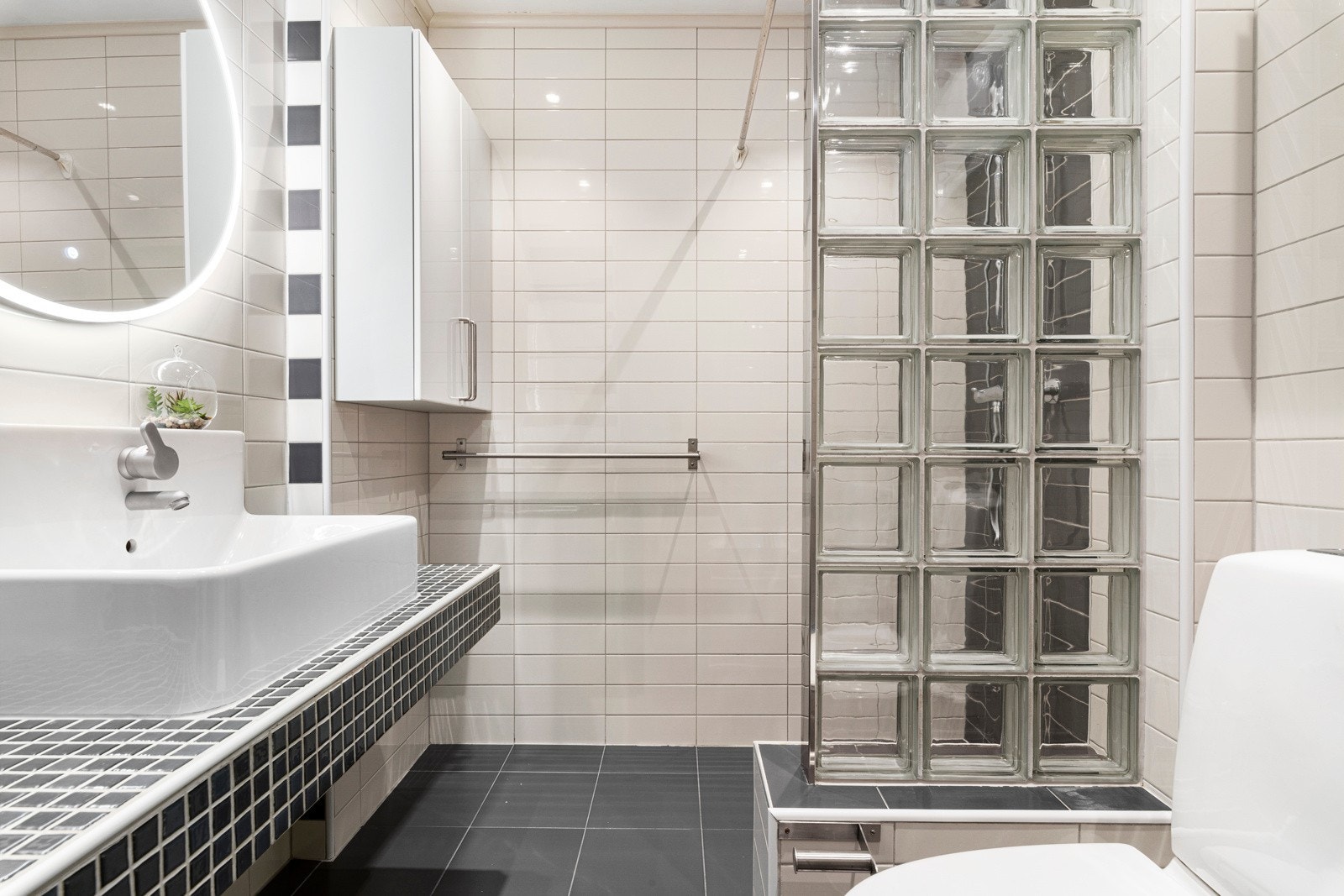 Badet er helfliset og har ikke-fungerende varmekabler. Her er det innredning med servant, sminkespeil, dusjnisje og wc. Galleribilde