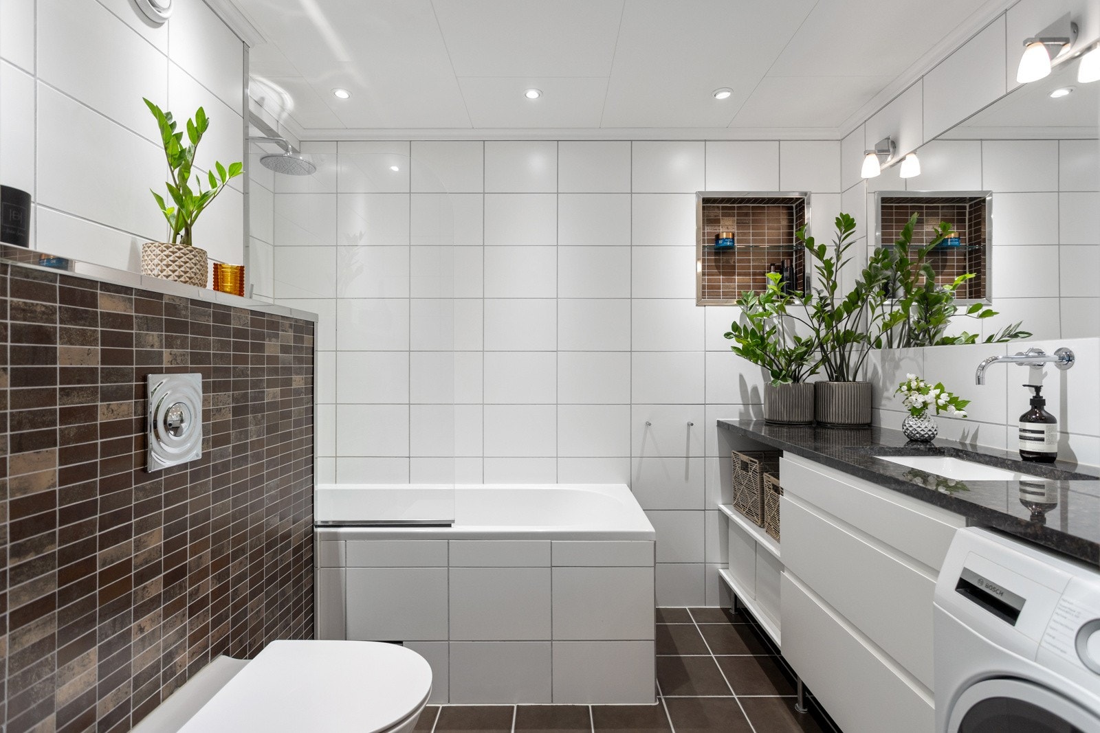 Moderne og lekkert flislagt bad med badekar, gulvvarme og downlights. Galleribilde
