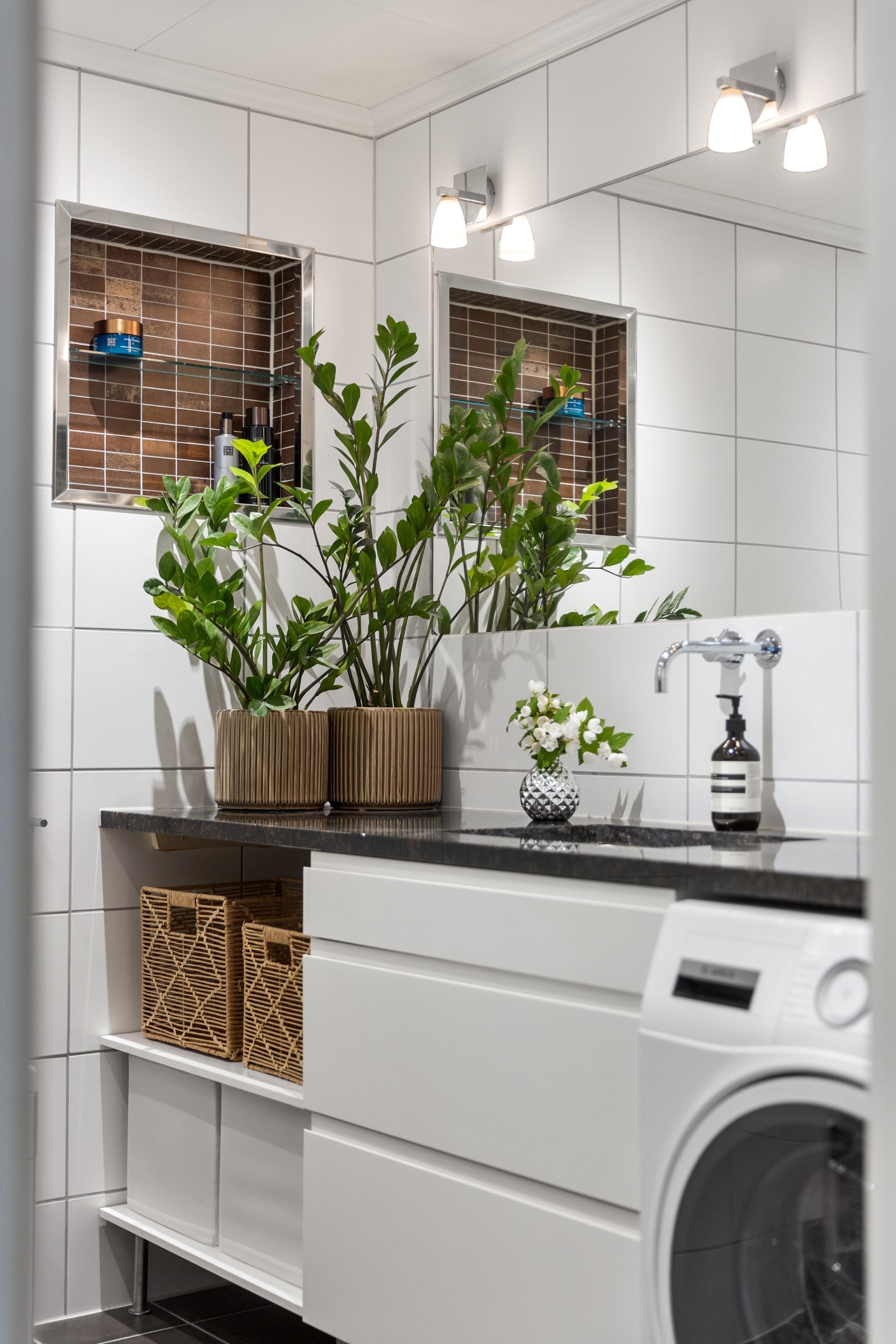 Badet er lekkert innredet med innebygde nisjer, opplegg for vaskemaskin under benkeplate i stein. Galleribilde