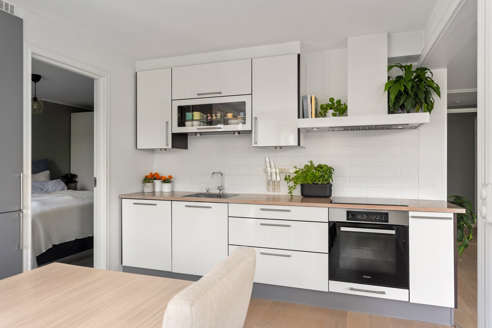 Moderne kjøkken med hvite glatte fronter og benkplate i heltre med fliser over. Galleribilde