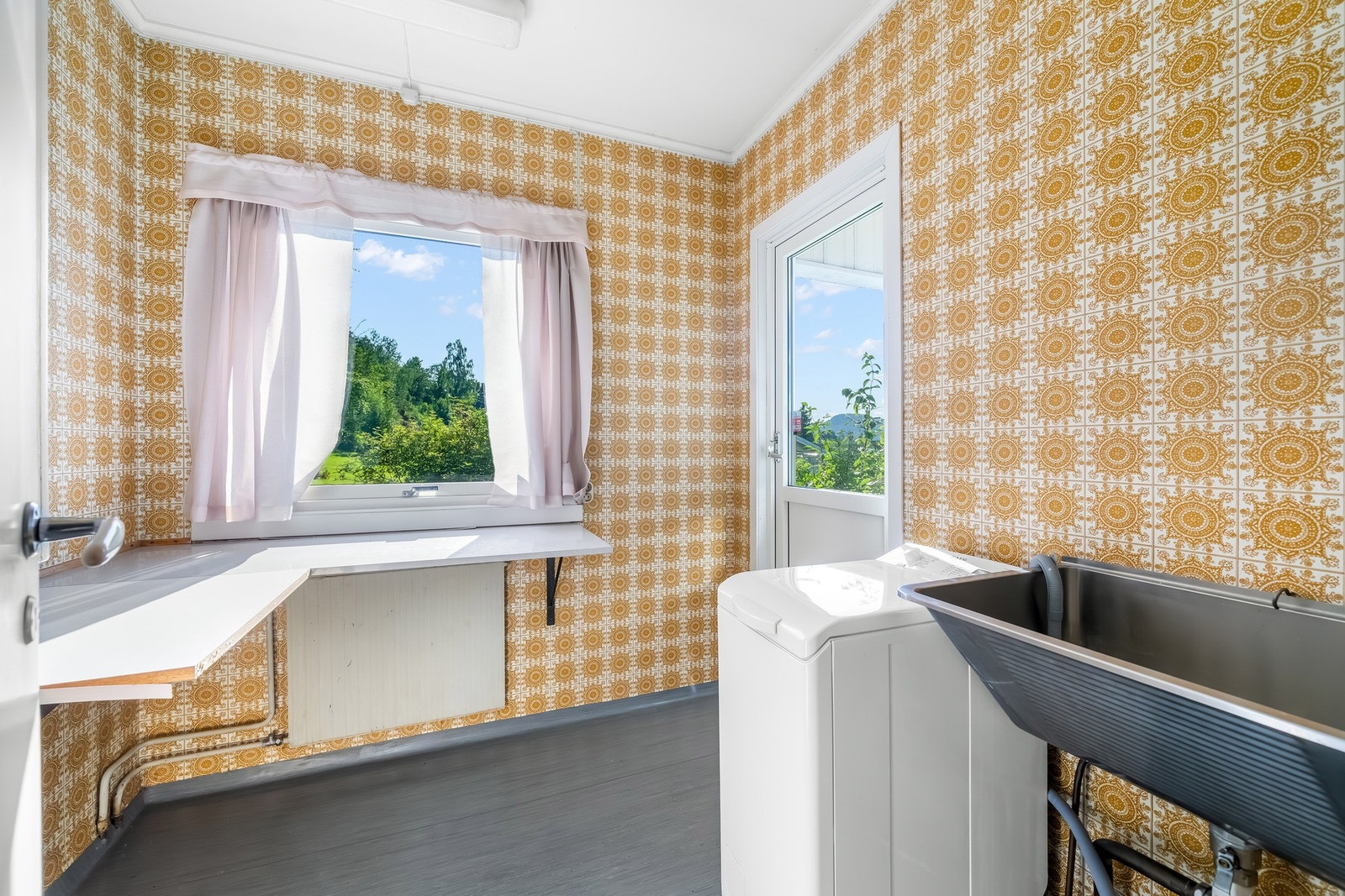 Vaskerom med utslagsvask, plass til skap og en egen brettestasjon. Utgang til den nordvestvendte overbygde terrassen. Galleribilde