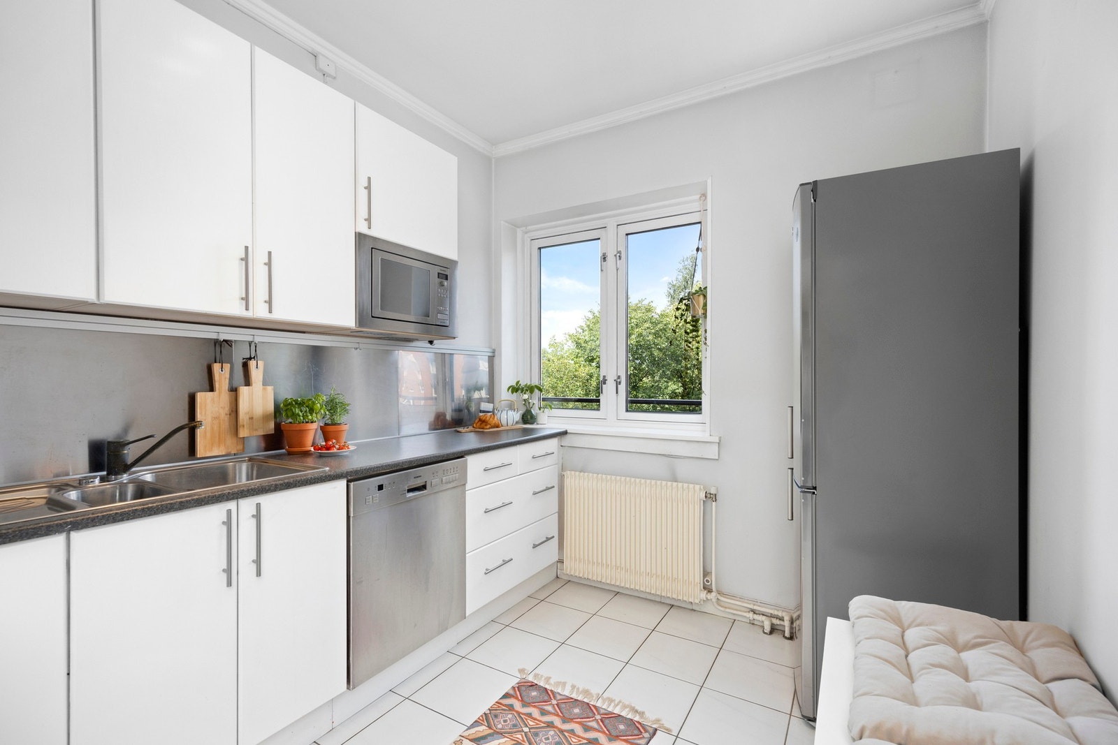 Kjøkkenet er plassert i et eget rom. Innredningen har glatte fronter og laminert benkeplate. Gulvfliser. Galleribilde