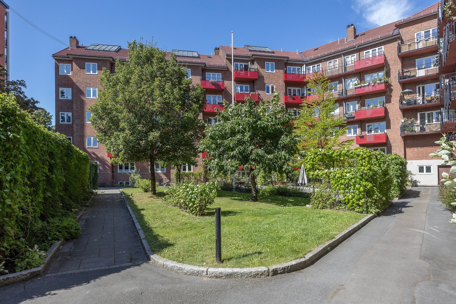 Nydelig gårdsrom med beplantning, gressplen og asfalterte interveier. Galleribilde