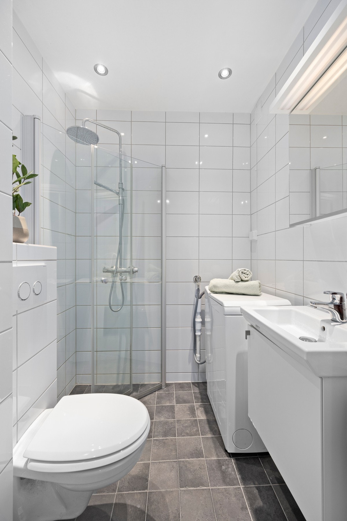 Pent flislagt baderom fra 2012 med vegghengt wc, dusjhjørne, servantskap og veggspeil med belysning. Galleribilde