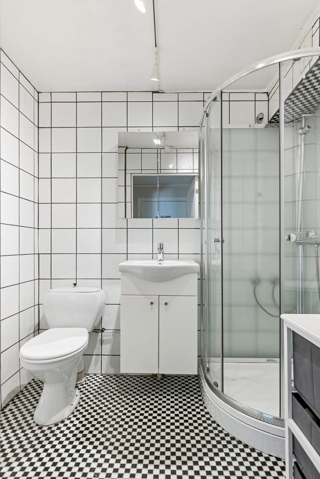 Baderommet har mosaikk fliser i sort og hvitt på gulvet og hvite fliser på veggene. Galleribilde