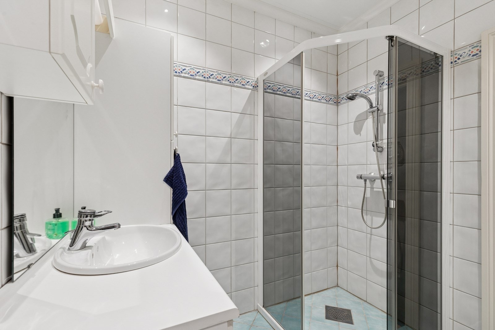 Baderom 1 - ved gang: rommet er utstyrt med gulvstående toalett, dusjhjørne og nedfelt servant med tilhørende underskap. Galleribilde