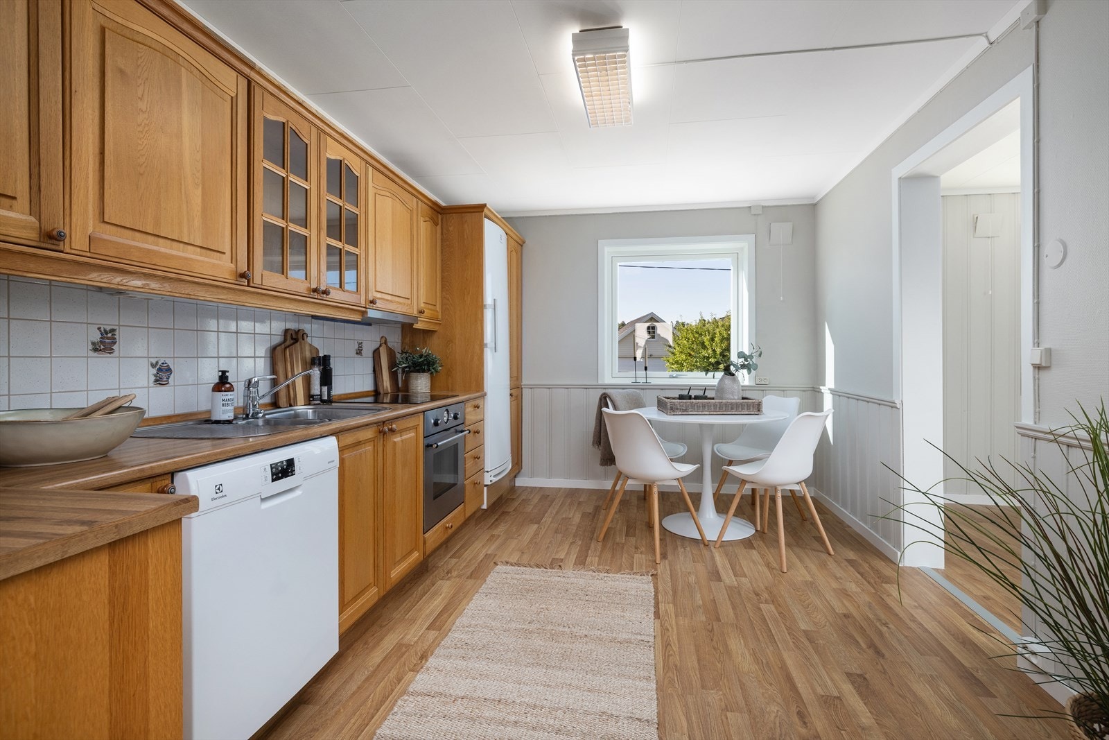 Kjøkkeninnredning i hovveddel med profilerte fronter i eik og laminat benkeplate med kjøkken beslag/kum i stål. Galleribilde