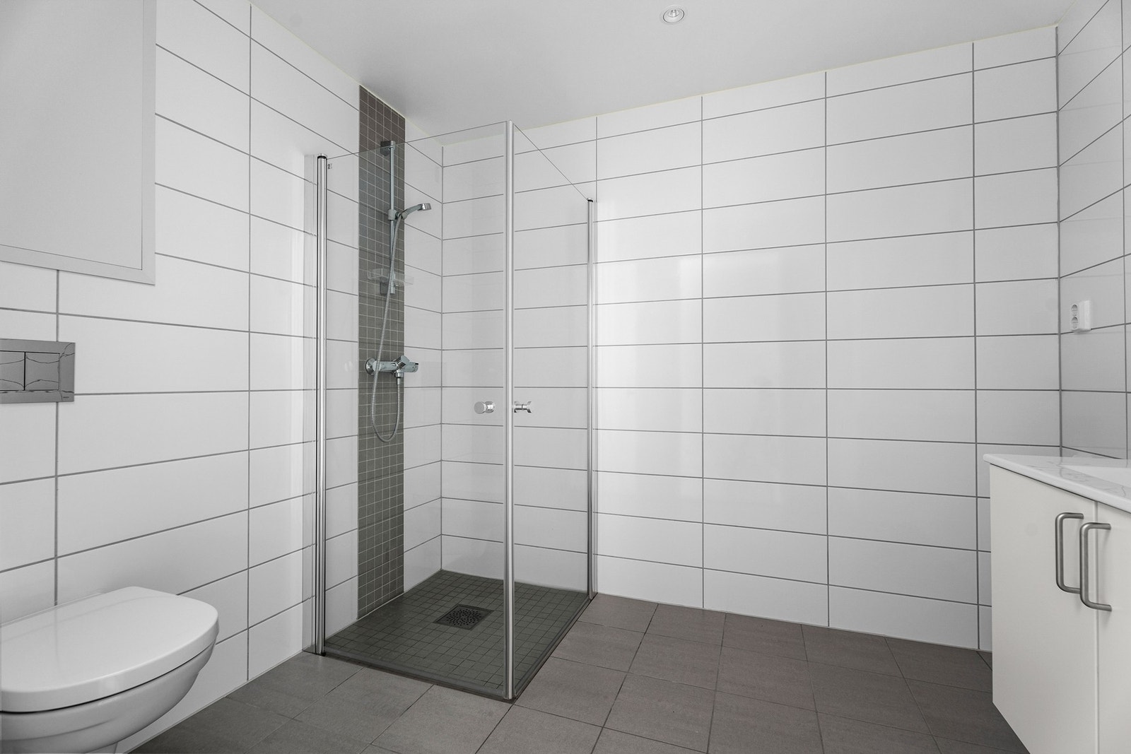 Badet inneholder wc, servant, speil og innfellbare glassdører i dusj. Galleribilde