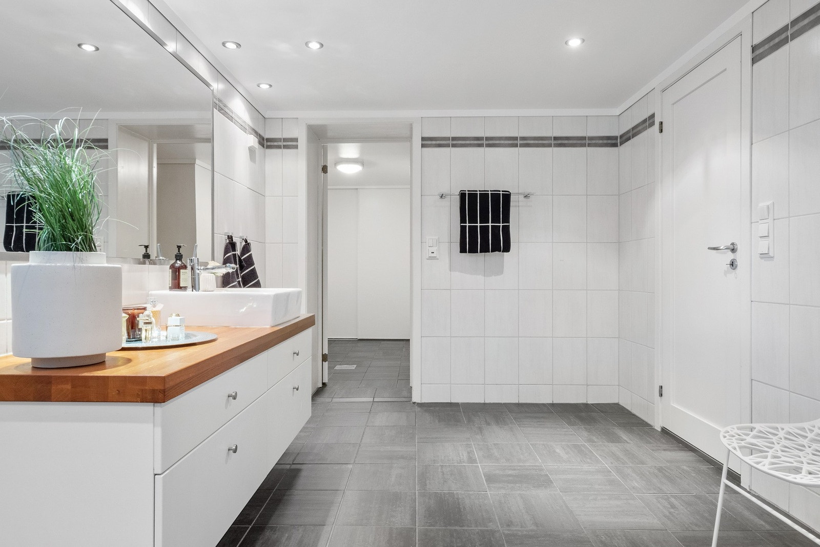 Baderomsinnredningen har hvite fronter og gyllen benkeplate, med toppmontert servant på skuffeseksjon. Galleribilde