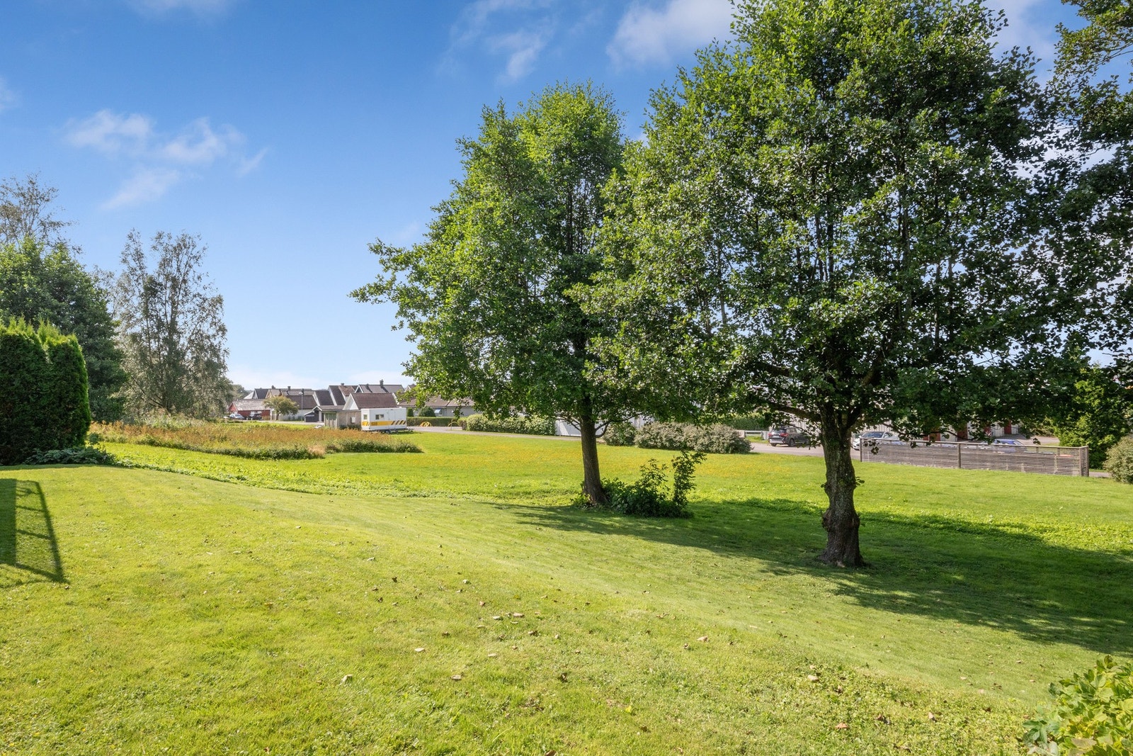Tomten er lett skrånende, solrik og pent opparbeidet med store plenarealer, prydbusker og høye, skjermende trær. Galleribilde