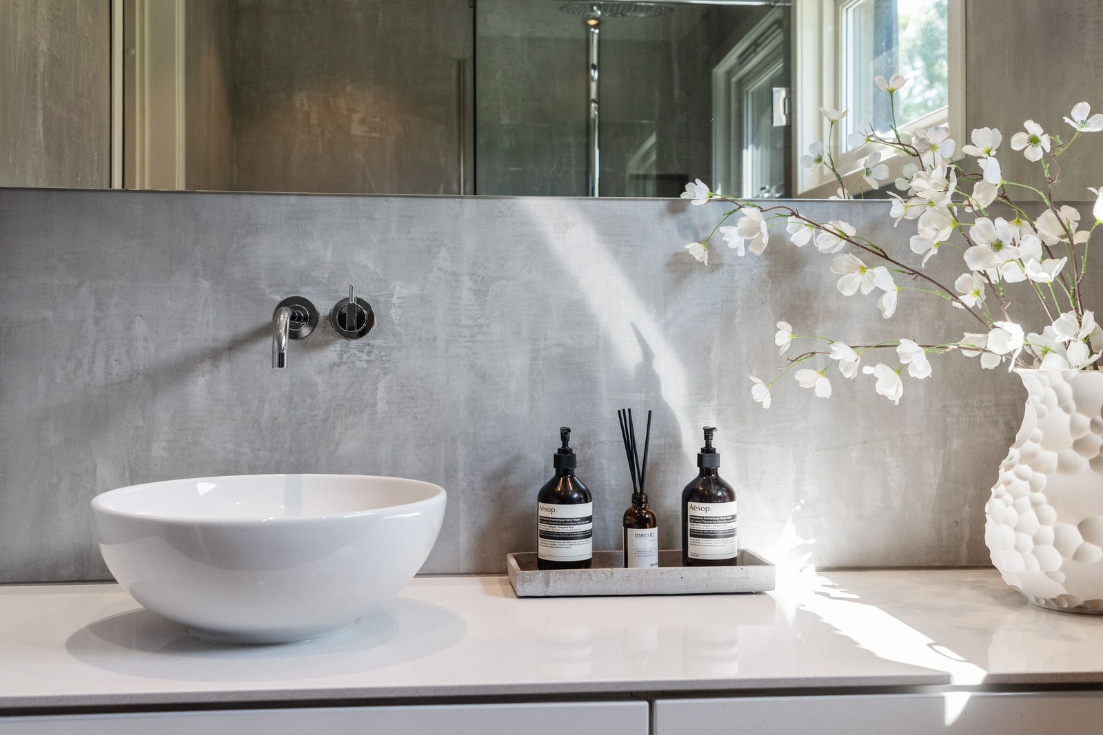 Innredningen består av en hvit, bred skuffeseksjon med toppmontert, rund servant, armatur fra Vola og et stort speil med god belysning over. Galleribilde