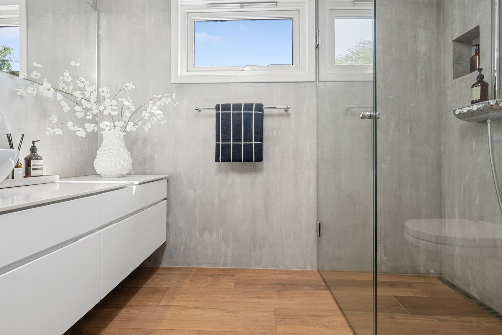 Badet i første etasje fremstår moderne og delikat, med vegger behandlet i lysegrå Beton Ciré og gulv belagt med italienske fliser med gulvvarme. Galleribilde