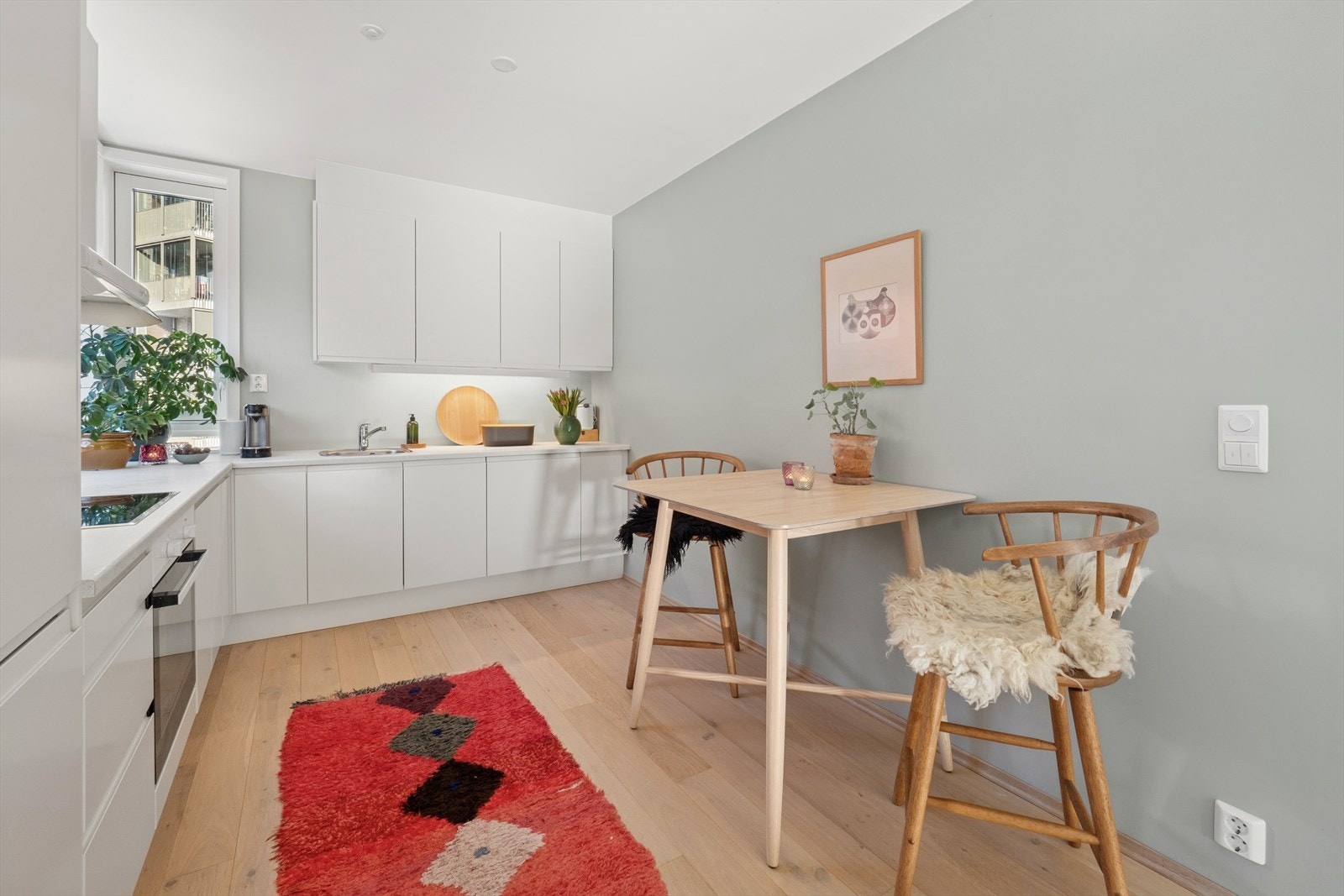 Her er det en stilfull kjøkkeninnredning utført med hvite, glatte fronter og lys laminat benkeplate med en kum, og integrerte hvitevarer. Galleribilde
