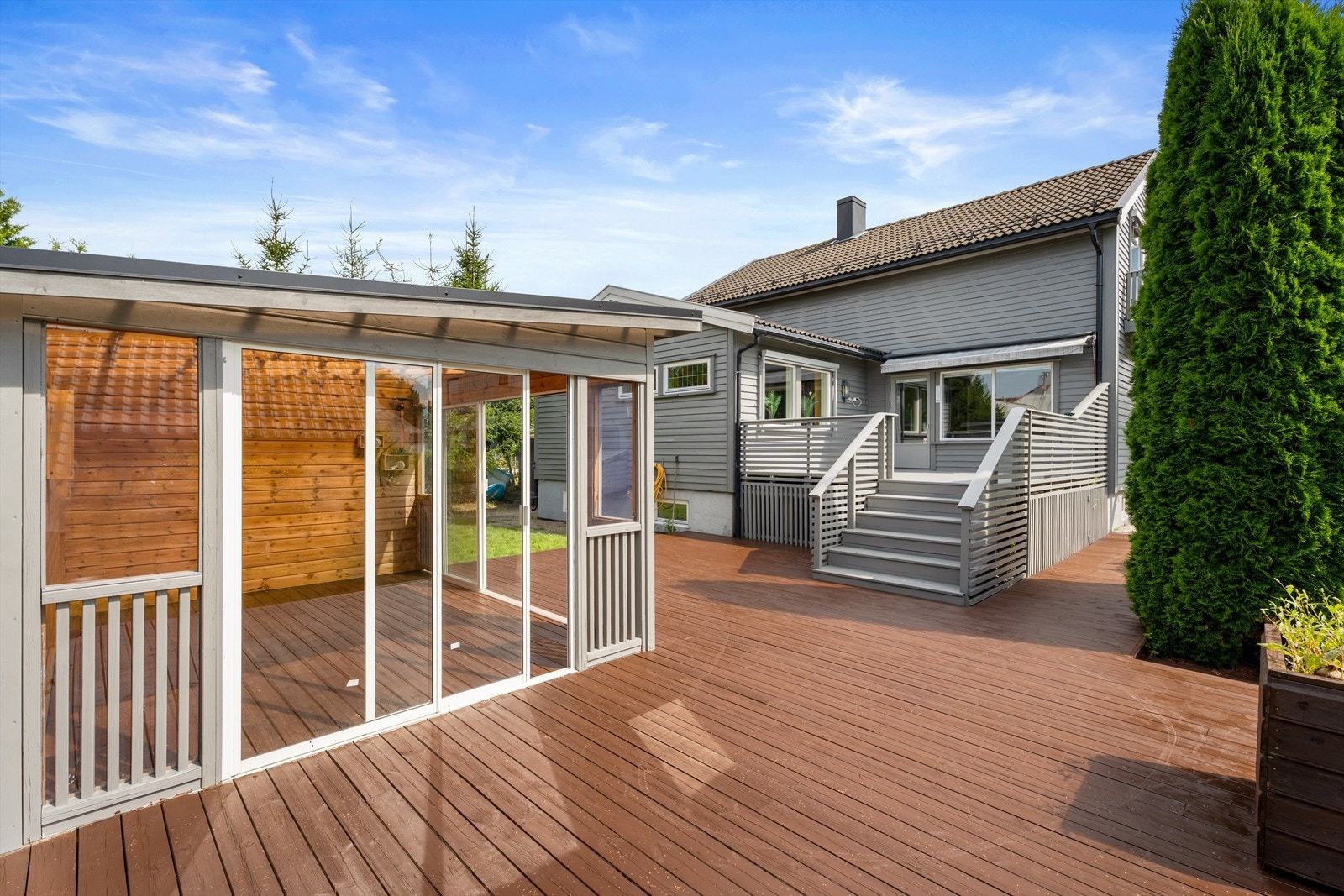 Pent opparbeidet tomt med gruset gårdsplass, heller, gressplen, gjerde, busker, trær, hekk og markterrasse Galleribilde