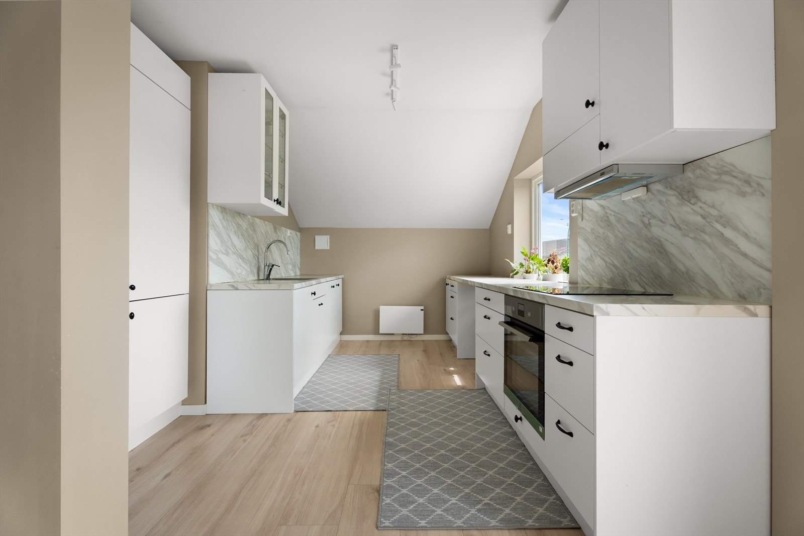 Kjøkkenet er fra Epoq og har moderne, hvite slette fronter, benkeplate i laminat og sprutsikre plater over benk Galleribilde