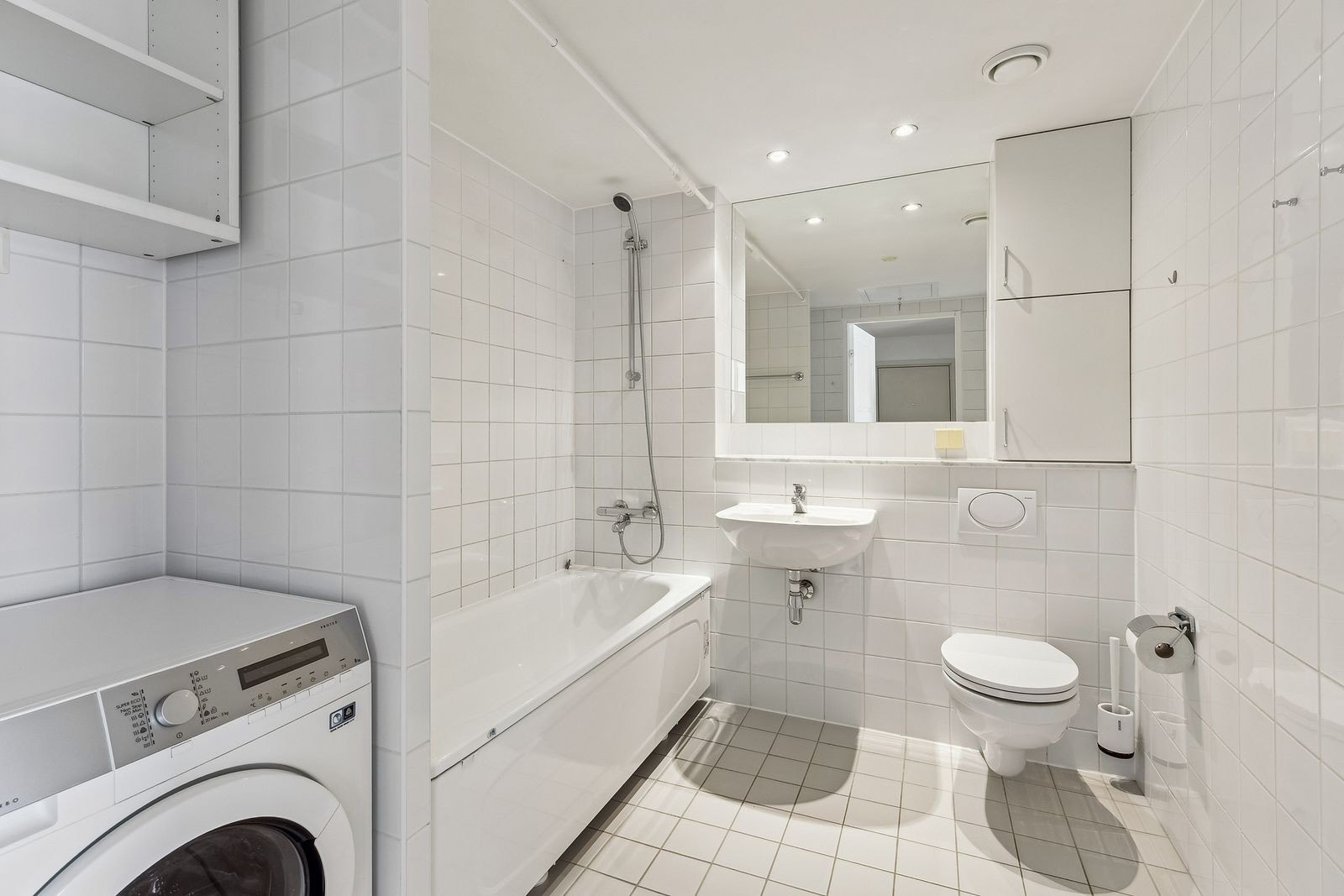 Flislagt bad med wc, servant, badekar og vaskemaskin Galleribilde