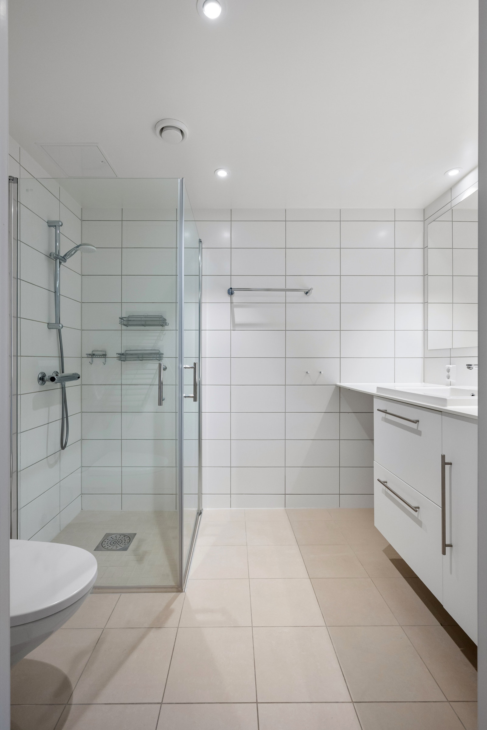 Stort, flislagt bad med moderne uttrykk og opplegg for vaskemaskin. Galleribilde