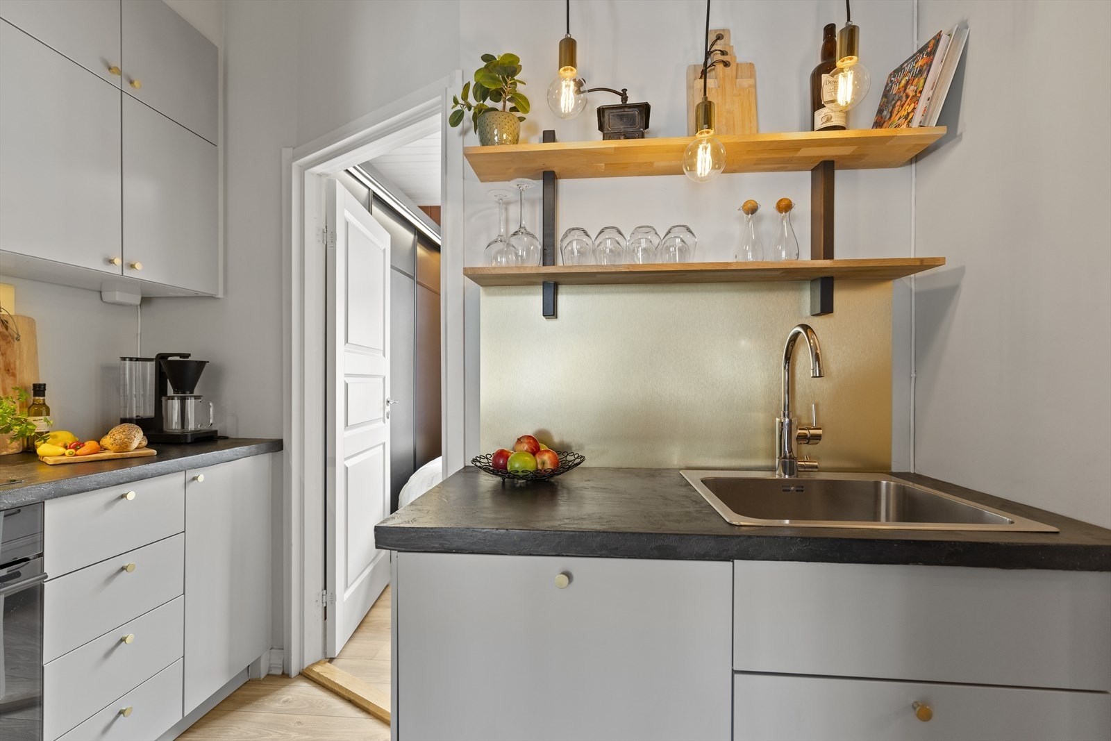 Lekkert funksjonelt kjøkken i lys grå med godt med oppbevaring i skap og skuffer samt praktiske løsninger med hyller til ekstra oppbevaring. Galleribilde