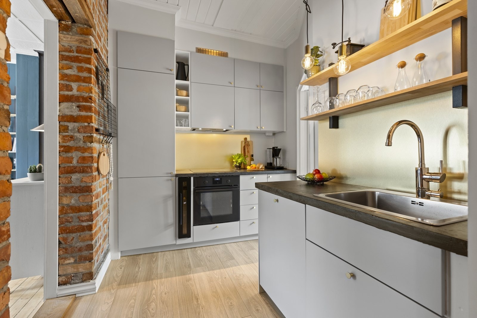 Pent Ikea kjøkken fra 2018 med glatte fronter og laminat benkeplate. Aluplater over kjøkkenbenk med belysning. Galleribilde