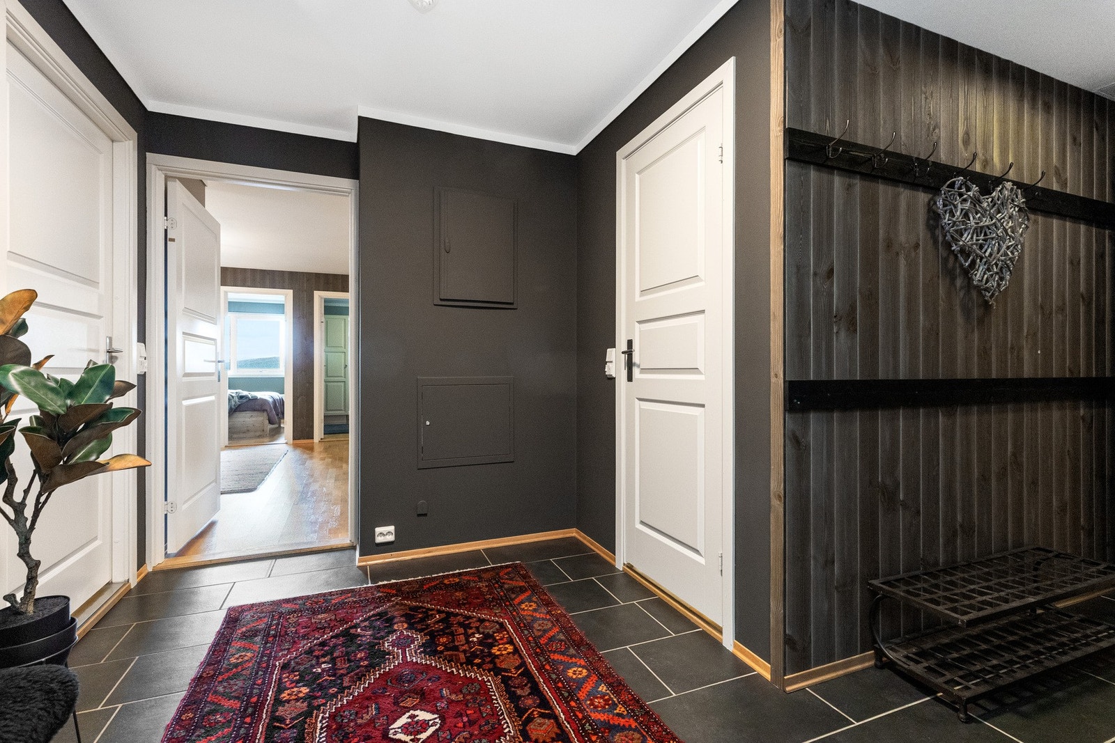 Gangen er romslig og praktisk, med grå fliser med varmekabler, dobbelt garderobeskap og knaggrekker - her er det god plass til både yttertøy og sko Galleribilde