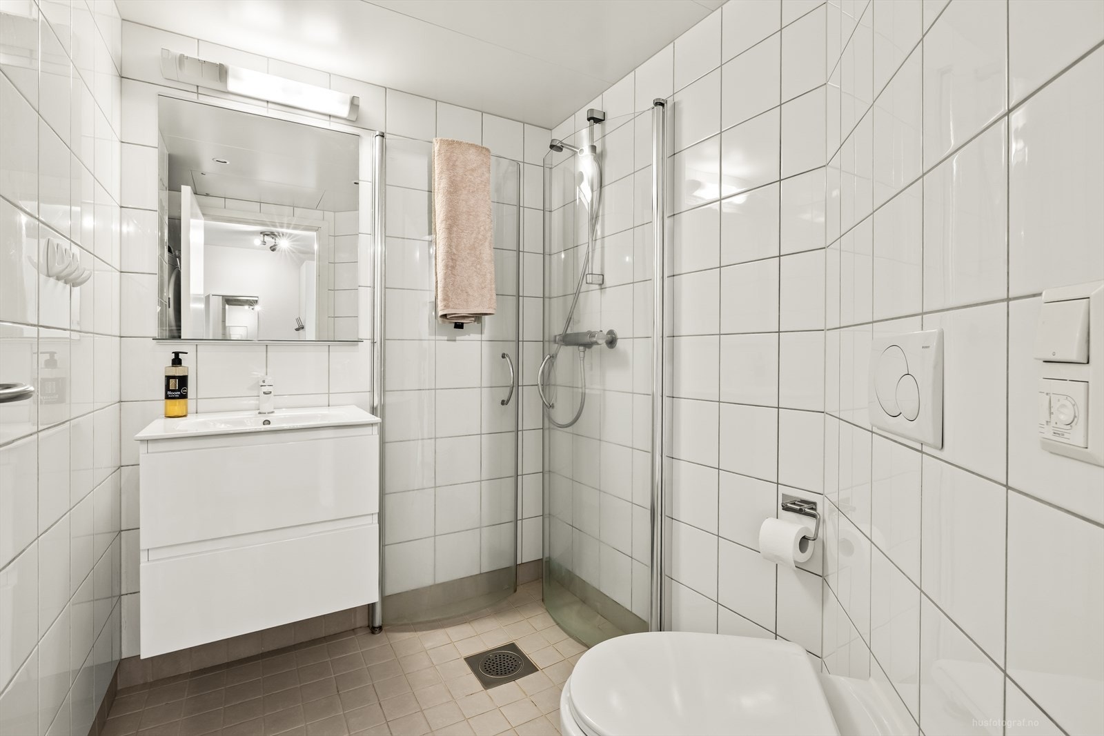 Pent bad med fliser på vegger og gulv og varmekabler i gulv. Veggmontert toalett. Dusjvegger/hjørne og baderomsinnredning med servant. Galleribilde