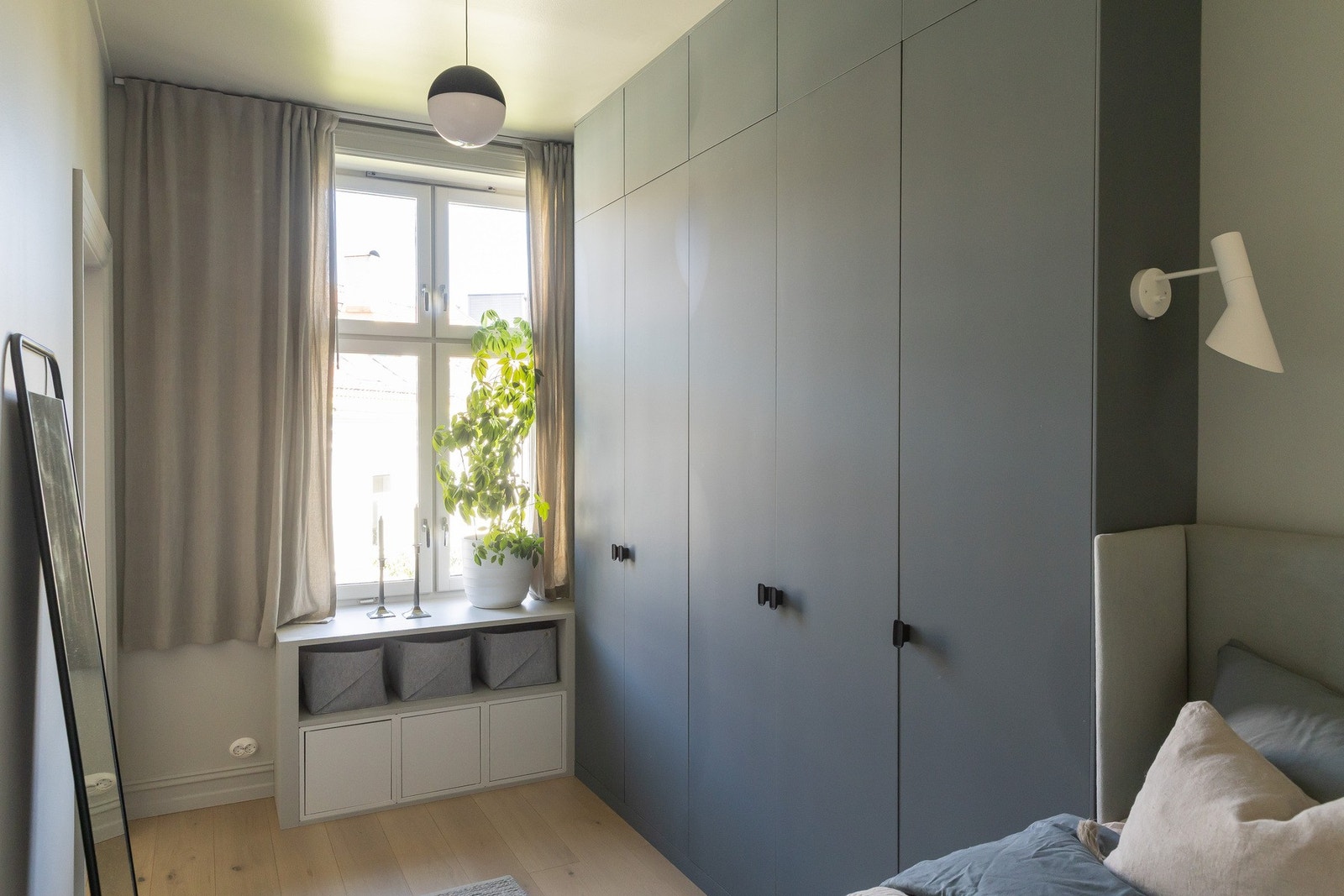 PAX-garderobeskap som strekker seg helt til taket og praktiske hyller under vinduet Galleribilde