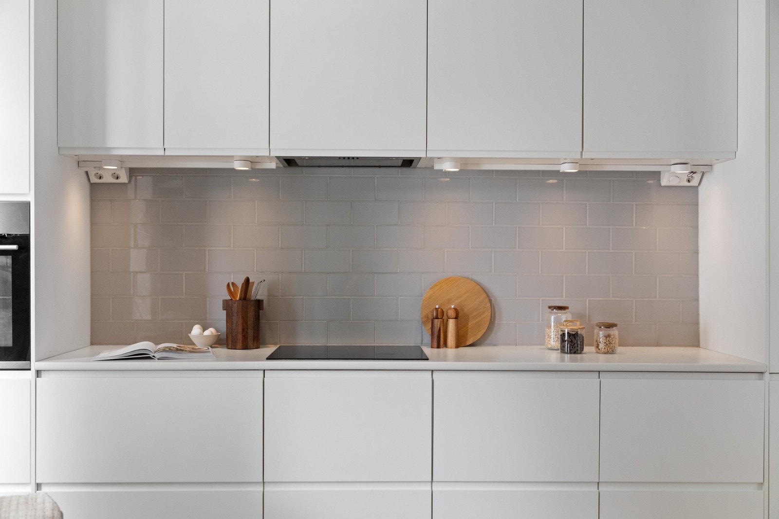 Innredningen har hvite, glatte fronter, takhøye skap og hvit laminatbenkeplate med nedfelt kum i stål. Galleribilde