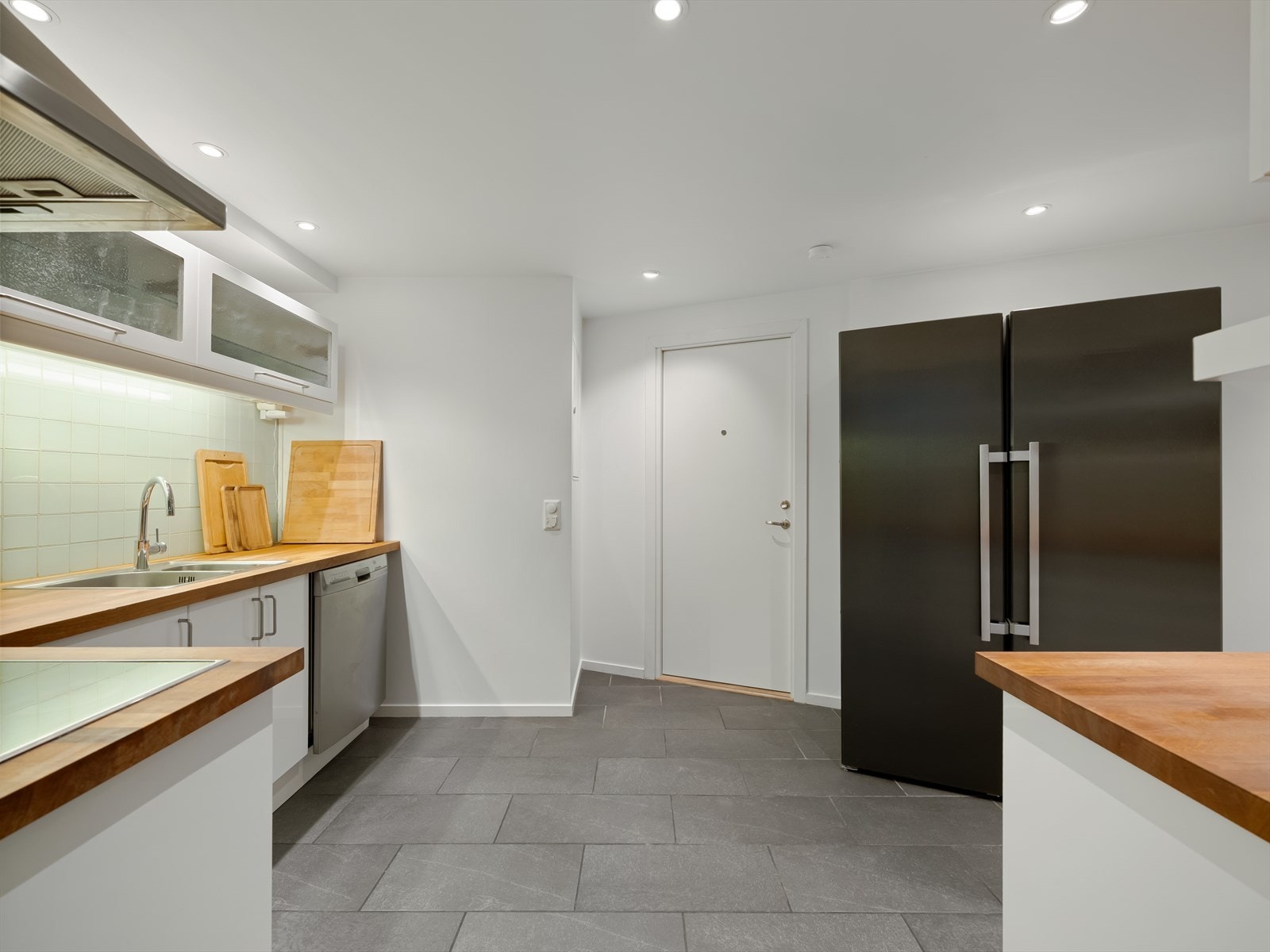 Kjøkkenet har fliser på gulv og lysemalte, slette veggflater. Rikelig med belysning i himling. Galleribilde