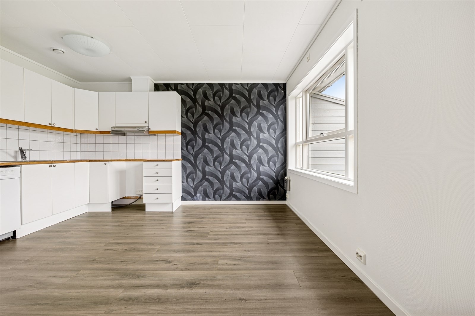 Videre har kjøkkenet åpen løsning for komfyr og oppvaskmaskin, samt plass til frittstående kjøleskap. Vegg over benkeplate er flissatt, noe som er praktisk ved matlaging. Det er avtrekk via balansert anlegg. Galleribilde