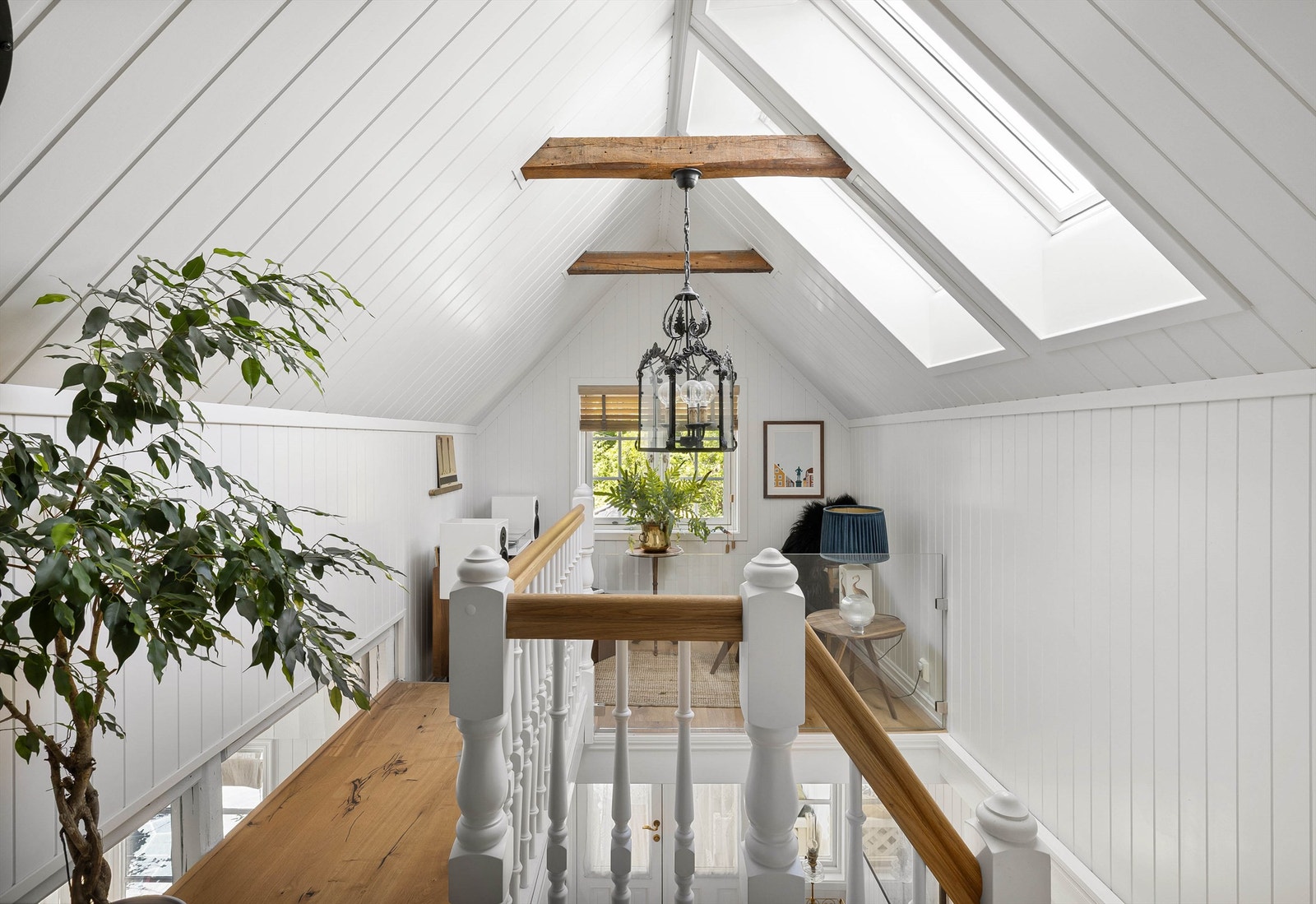 Stilfull trappegang med synlige takbjelker og takvinduer som slipper inn rikelig med dagslys. Galleribilde