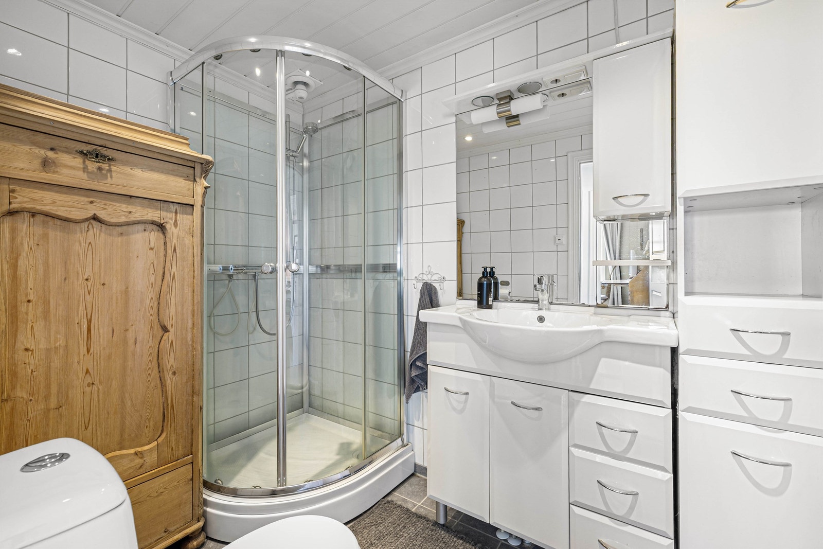 Pent, flislagt bad med dusjkabinett og god oppbevaringsplass - funksjonelt og innbydende. Galleribilde