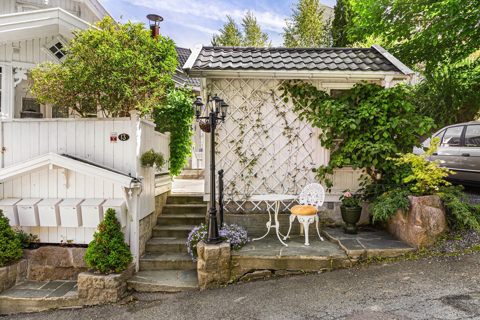 Stemningsfullt inngangsparti med skiferstein, klatreplanter og en koselig sittegruppe - et innbydende førsteinntrykk. Galleribilde