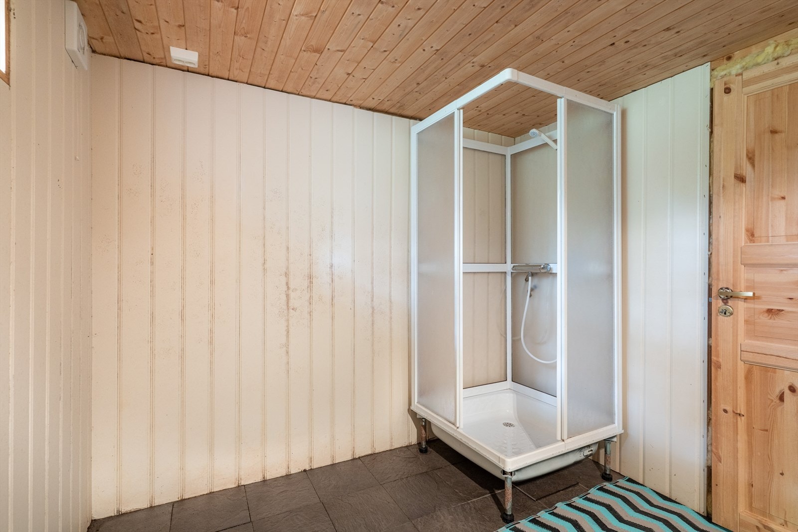 Det er innredet med et enkelt baderomsmøblement med underskap, nedfelt servant og speilflate med belysning over vask. Videre er det dusjkabinett i det ene hjørnet, mekanisk avtrekksvifte og opplegg for vaskemaskin. Galleribilde