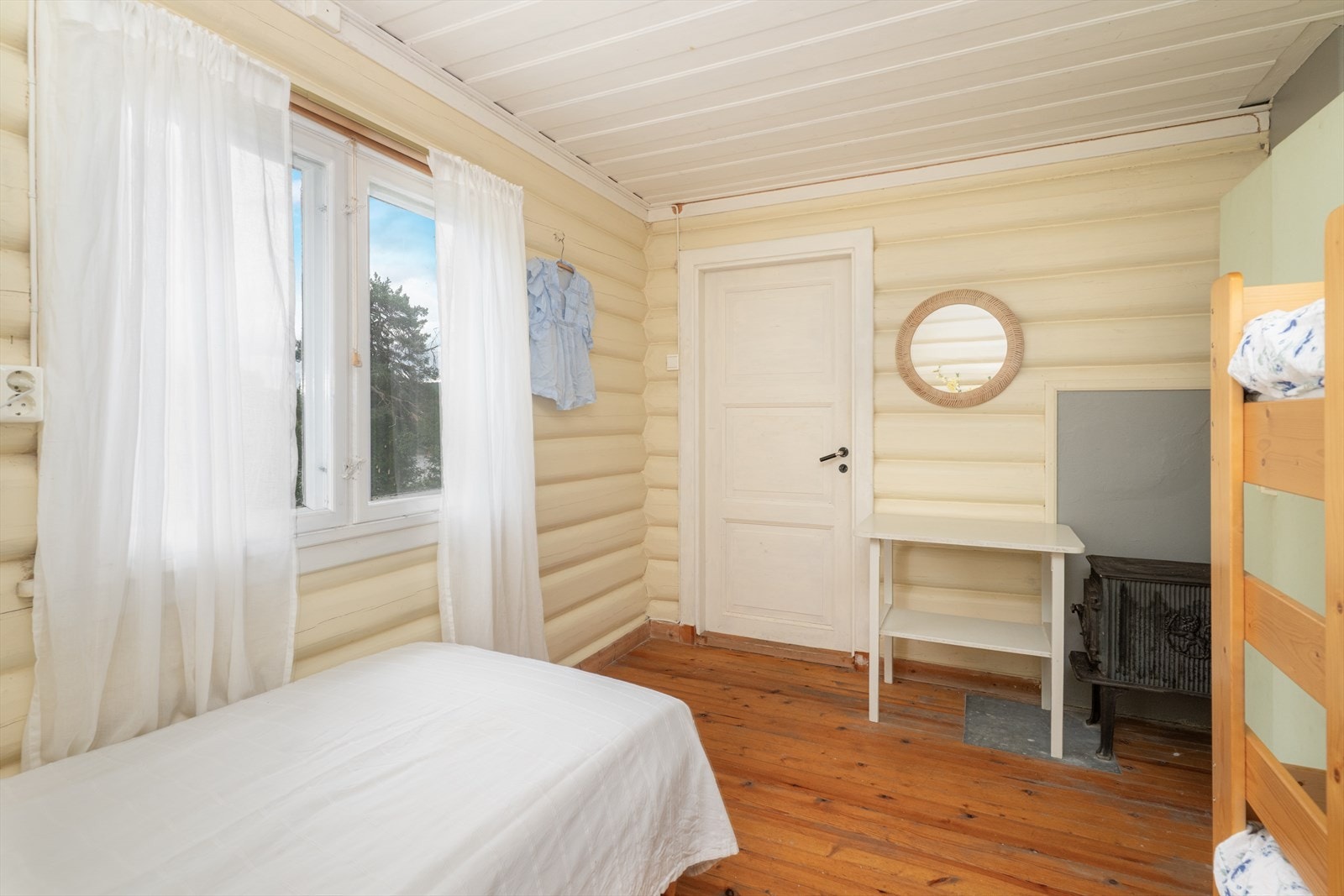 Boligens sikringsskap med automatsikringer er plassert på soverommet. Det er en eldre vedovn i rommet. Galleribilde