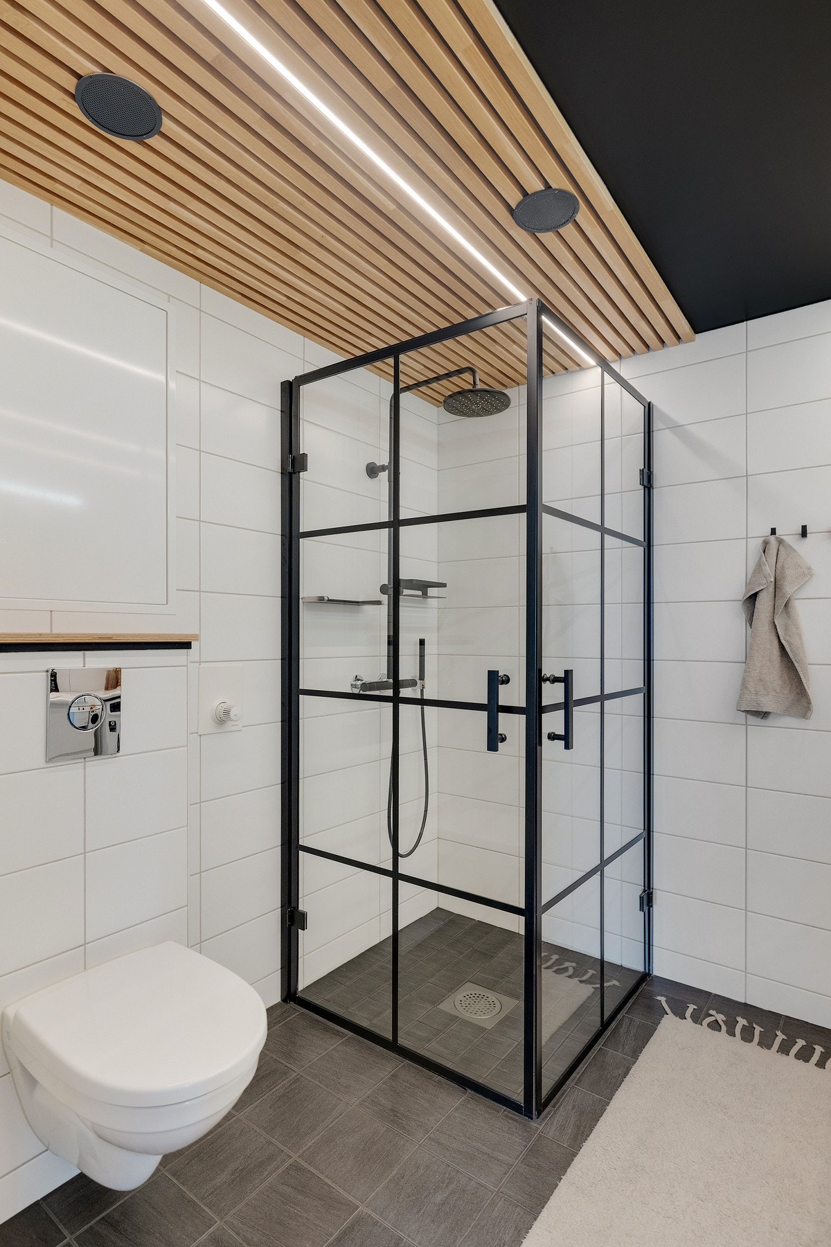 Dusjsonen er nedsenk og har glassvegger med sort stålramme og regndusj. Galleribilde