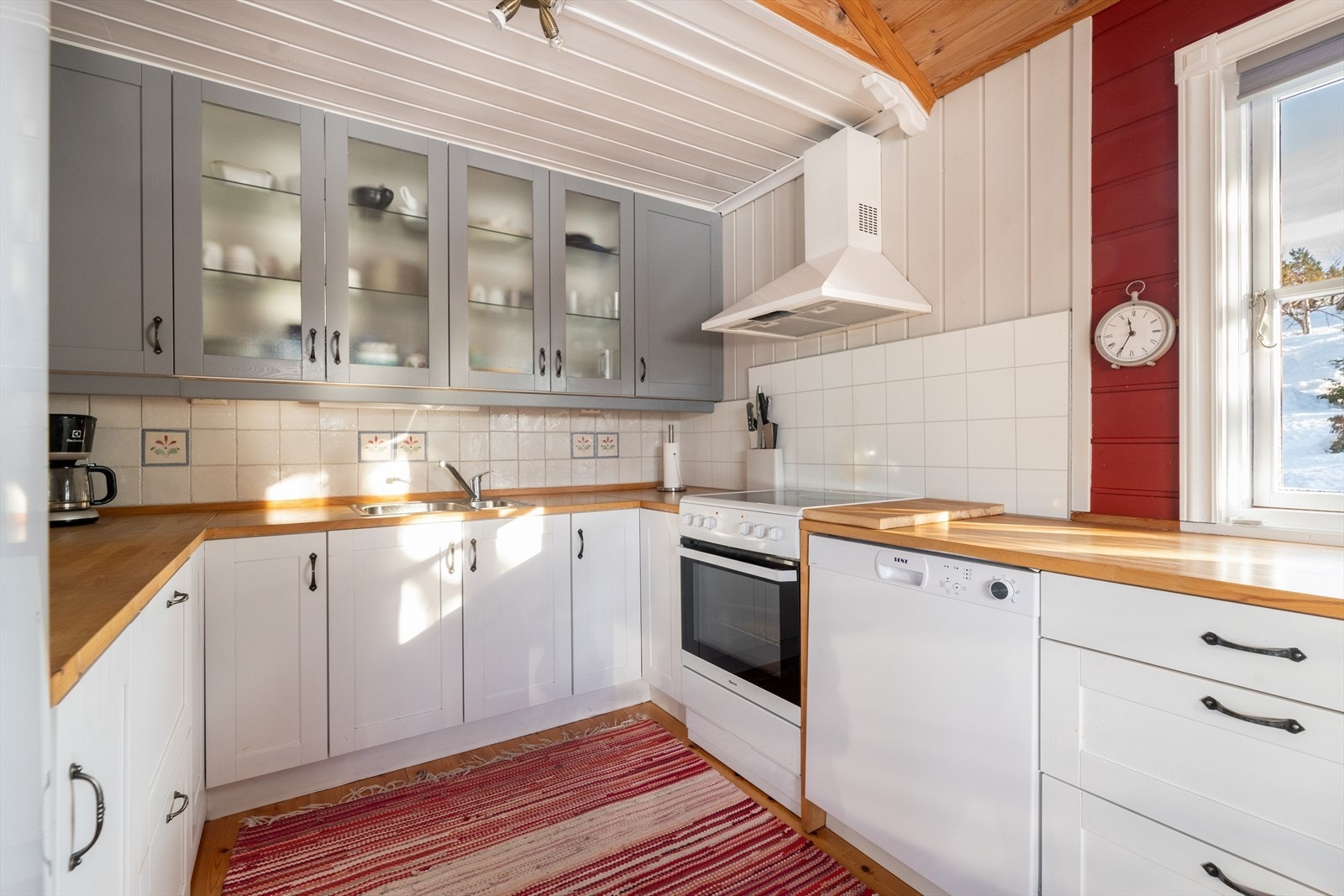 Heltre benkeplate med gode arbeidsflater og nedfelt oppvaskkum i rustfritt stål. Over kokesonen er det montert kjøkkenventilator. Galleribilde