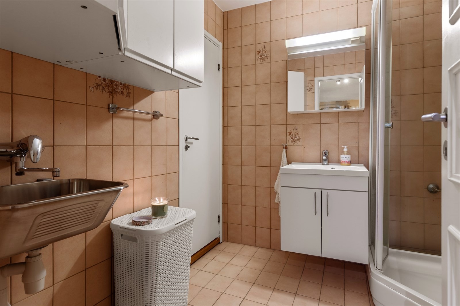 Flislagt bad som består av servant, dusjkabinett, utslagsvask, vegghyller og opplegg for vaskemaskin og tørketrommel Galleribilde